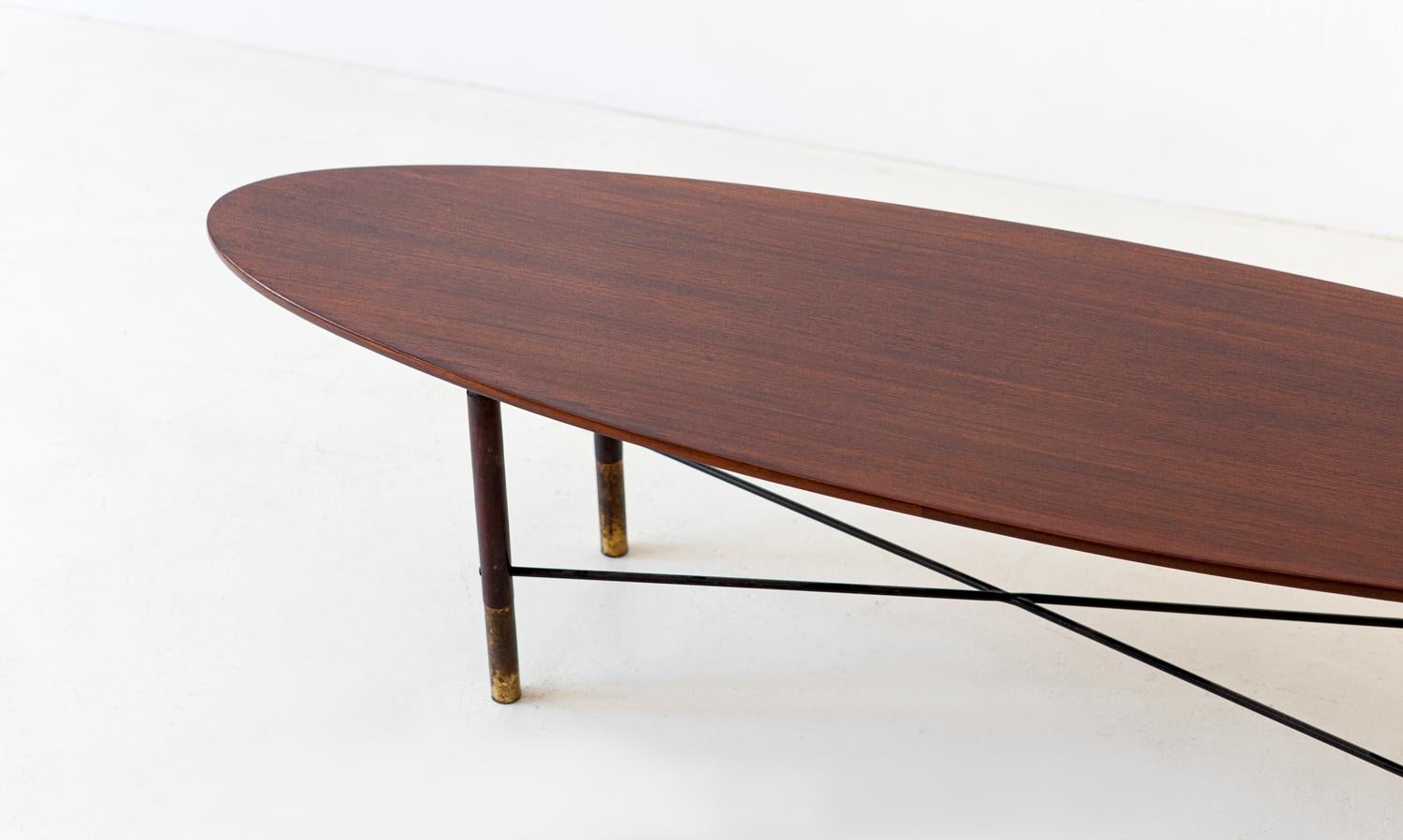 A long and low table manufactured in Italy in the 1950s
Brass feets, solid teak legs and black enameled iron crossed rods frame, wooden oval plane.
 