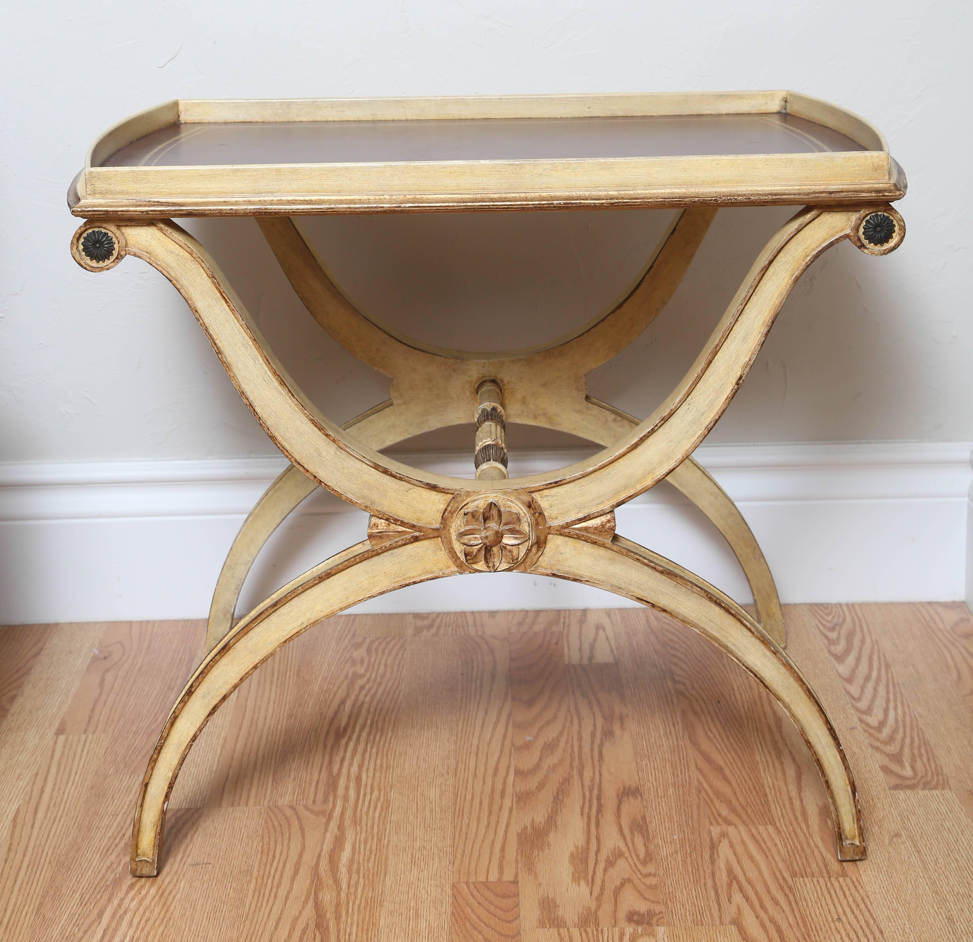 Curule style painted and gilded wood tray table with embossed deep red leather top. This Neoclassical style table would make a great dry bar for your living room or library.