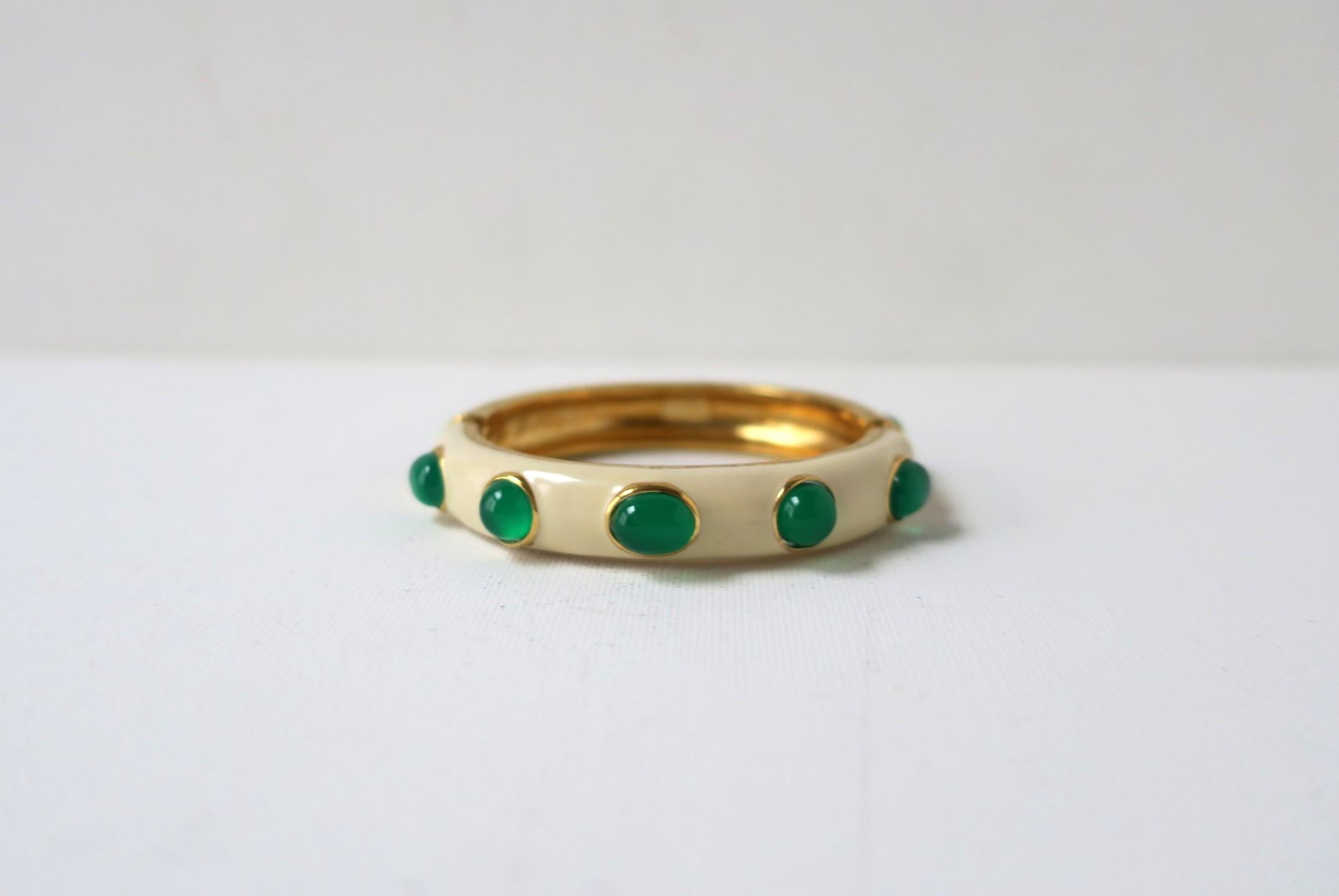 Una pulsera brazalete italiana de imitación de esmeralda con cabujón, bonita y bien hecha. Fabricado en Italia. El brazalete es de un tono crema esmaltado, con piedras de resina cabujón de imitación de esmeralda alrededor, acabadas en un metal