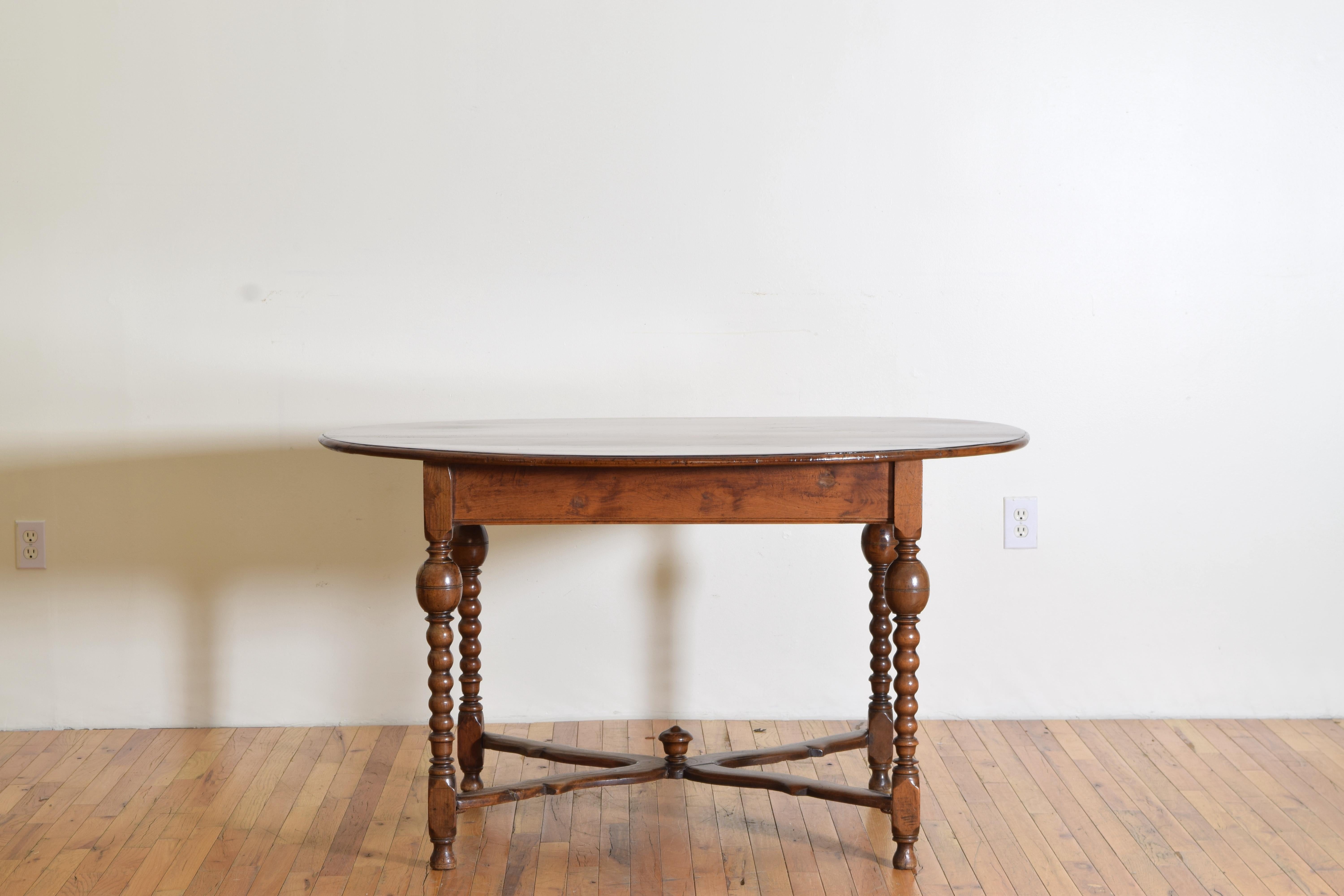 having an oval top with a thin molded edge above a rectangular frame raised on masterfully turned legs joined by a shaped x-form stretcher with a centered finial, resting on small bun feet.