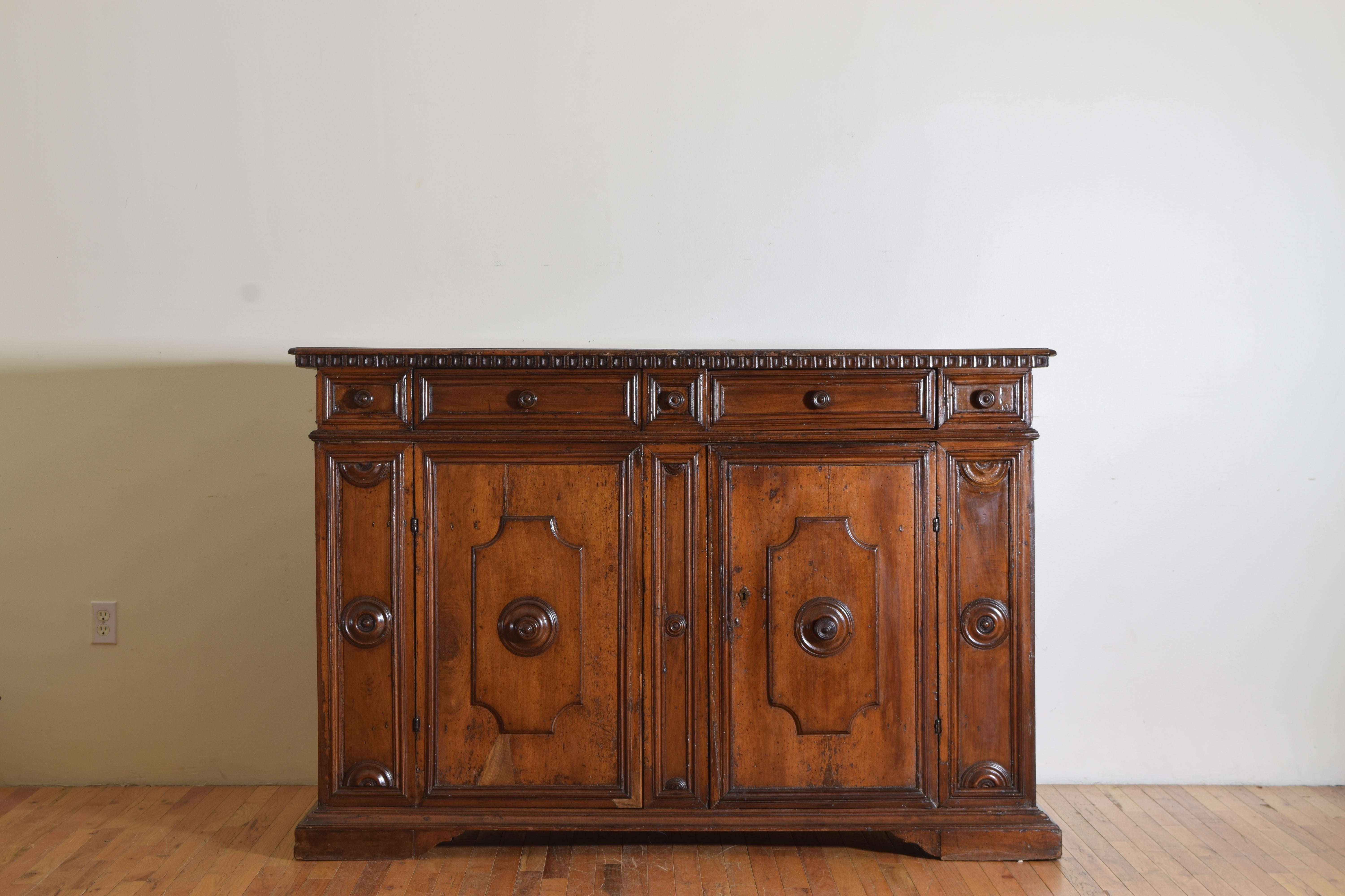 Having a rectangular top above a conforming case housing two drawers (with three faux drawers) over two doors, the case decorated with turned roundels and half roundels, raised on bracket feet.
