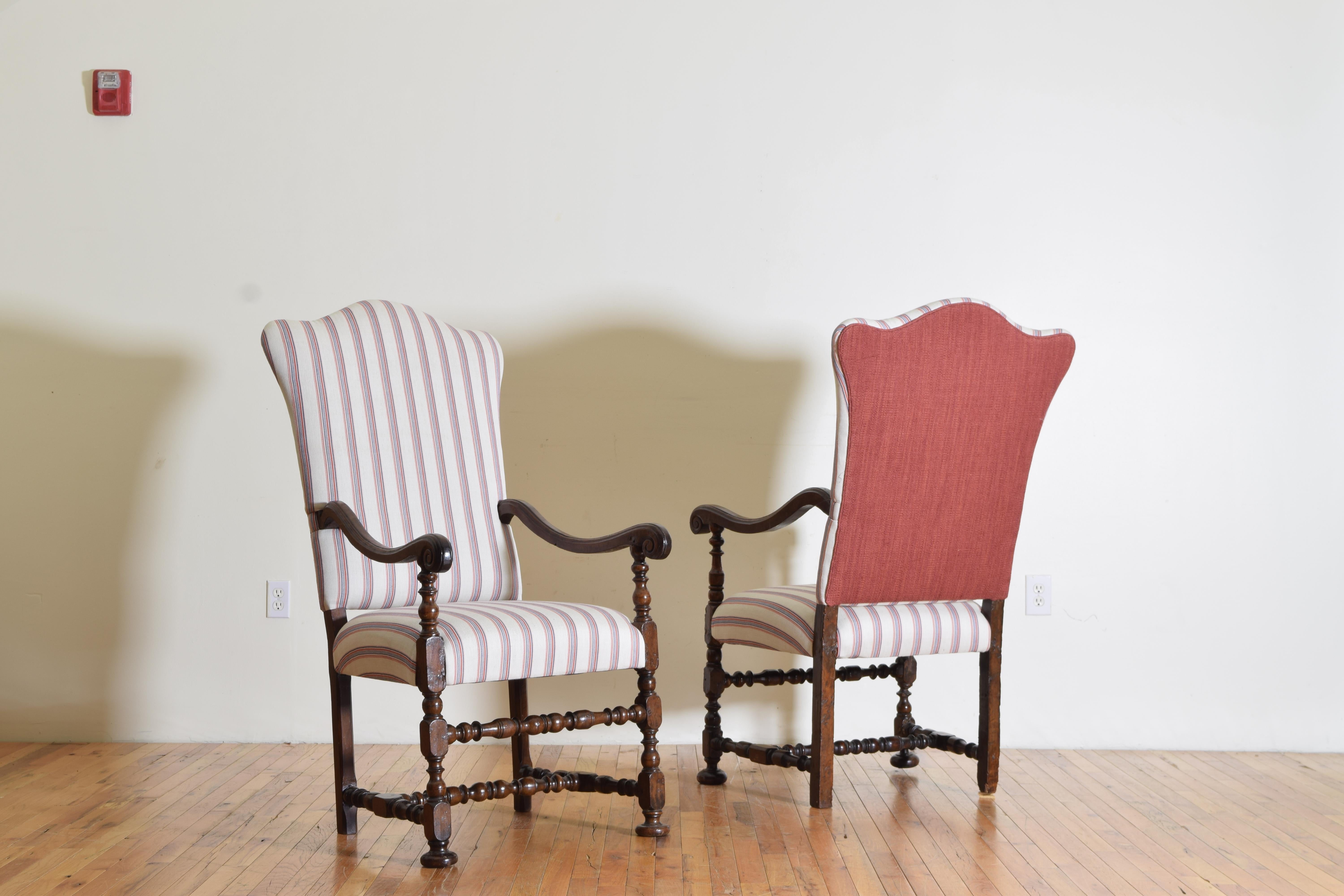 A handsome pair of finely carved and highly styled armchairs with etching on the arms where the walnut meets the backs. Newly upholstered and strengthened.