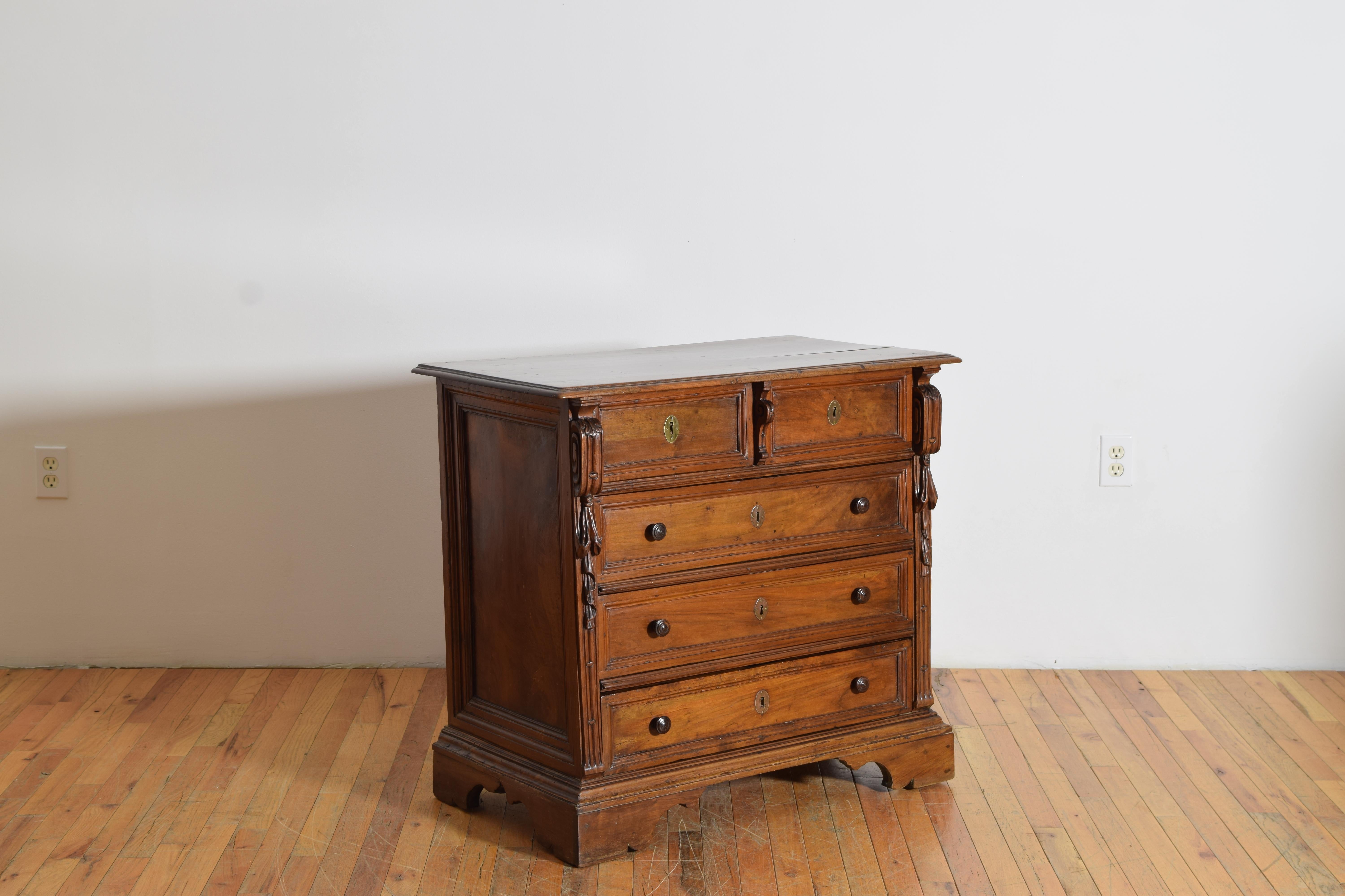 Having a rectangular top with molded edge above a conforming case housing two over three drawers the upper front with carved details, raised on bracket feet