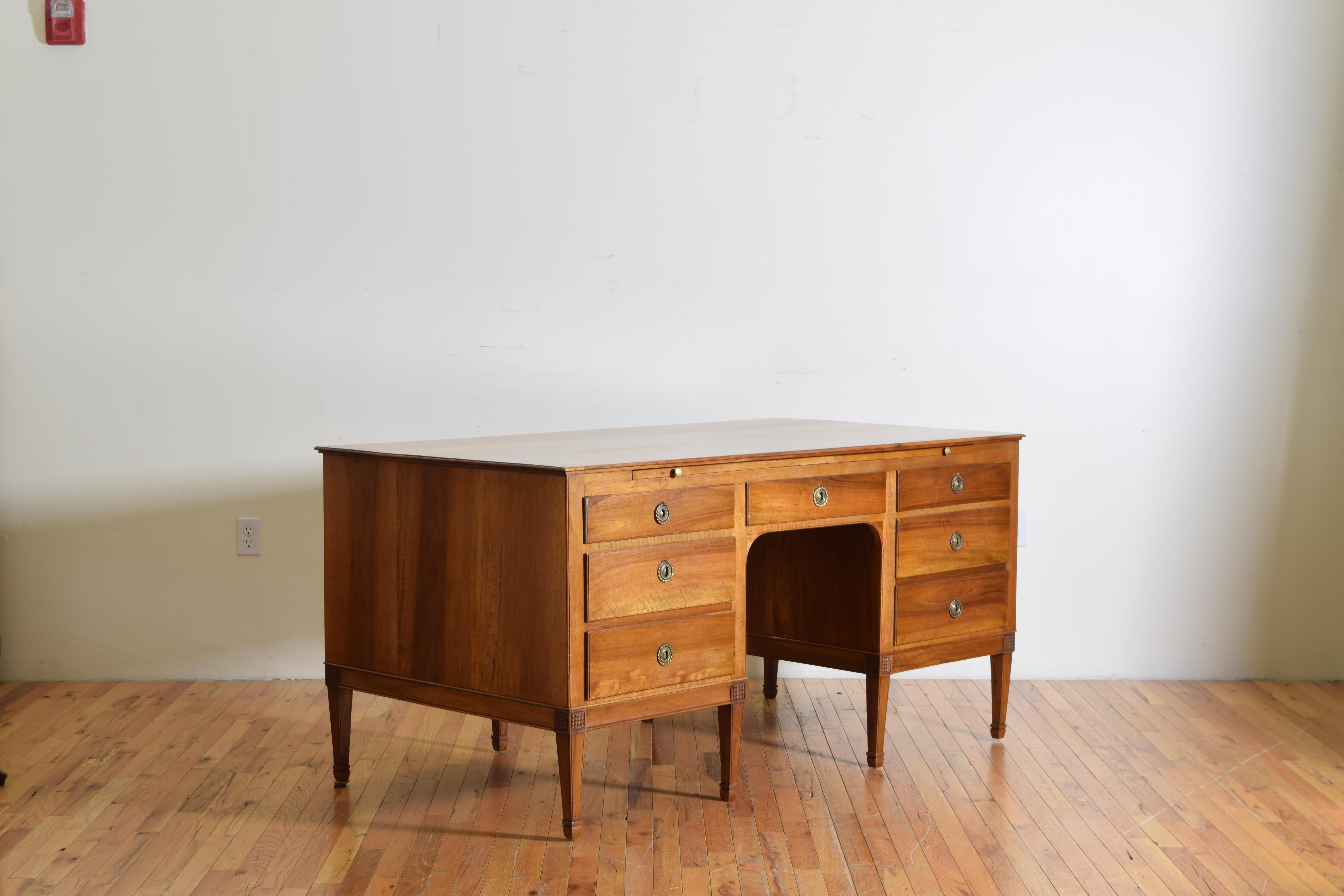 This large and in charge desk has writing slides on both sides and drawers opening from one side, constructed of solid walnut, the drawers with molded edges, working locks in every drawer, raised on square tapering legs with carved rosettes and