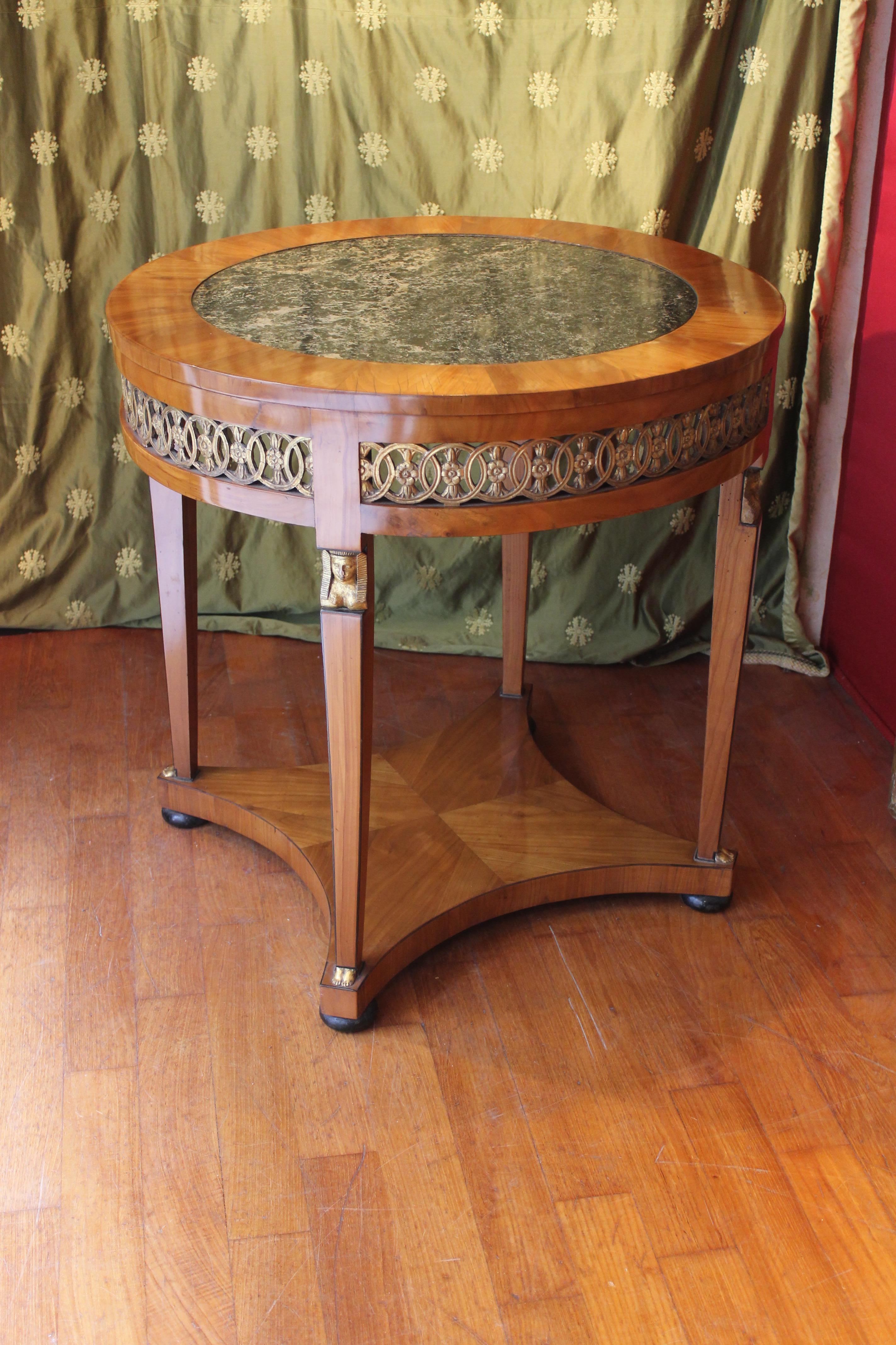 This outstanding cherrywood and giltwood round centre table belongs to the Empire period called 