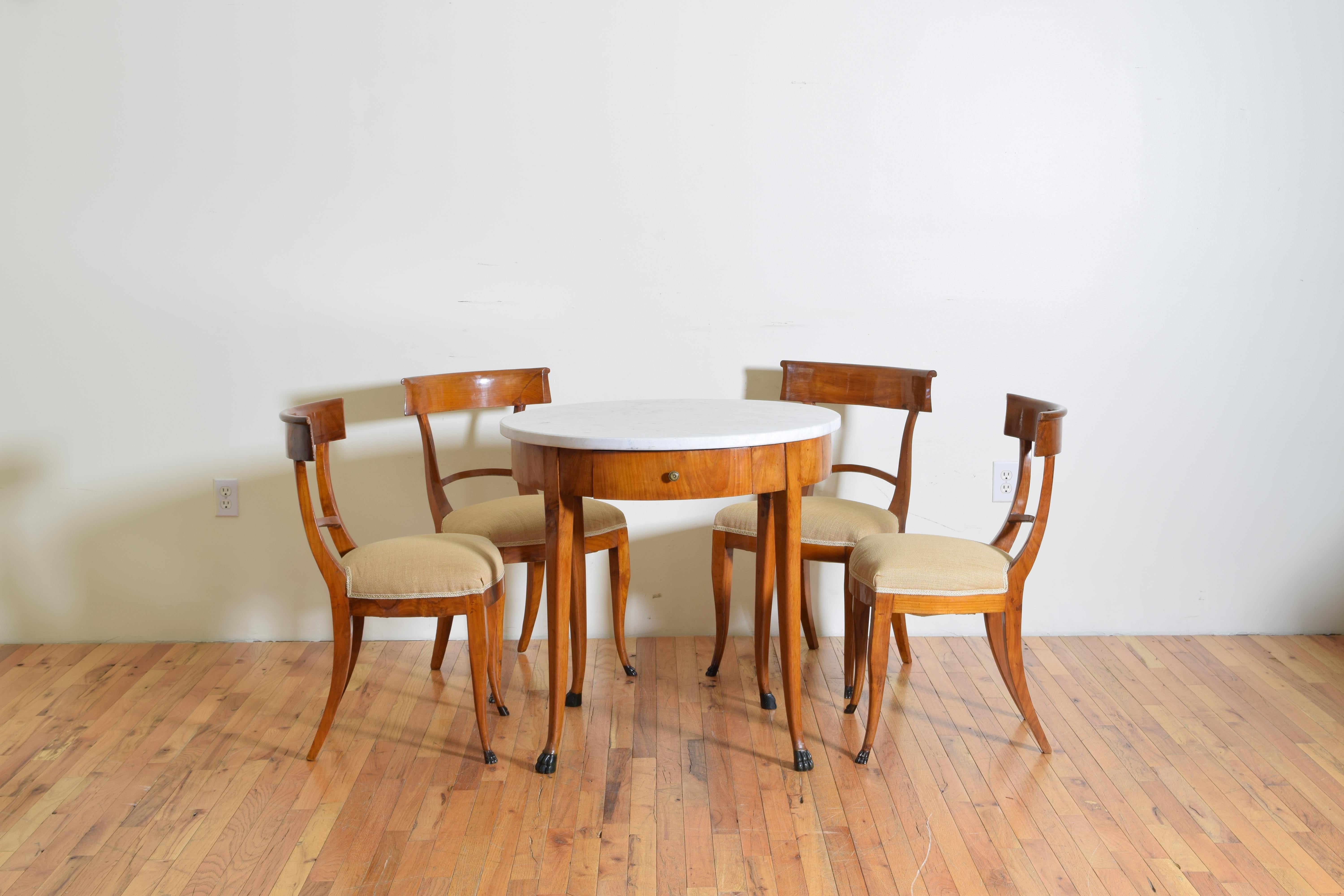 from Western Tuscany, probably Lucca, Italy, the table having its original white marble top atop a circular banded table housing one drawer with cherrywood legs and veneered sides, the paw feet are ebonized, the corresponding set of 4 chairs having
