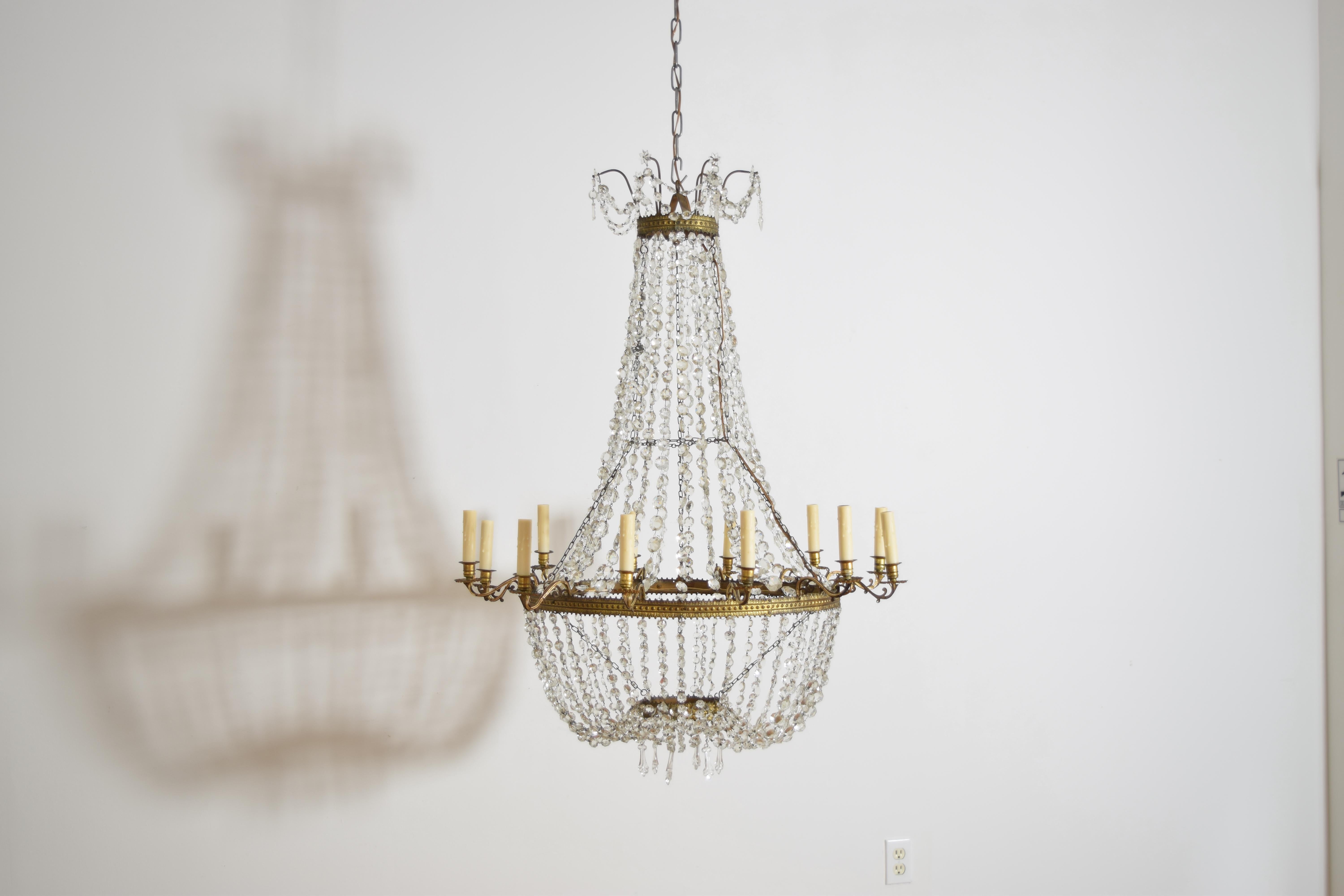 datant de la période de l'Empire italien, ce lustre conserve ses anneaux en métal doré et sa chaîne de perles de verre d'origine, ainsi que des prismes de verre uniques. Le sommet est une sorte de couronne utilisant une chaîne de perles pour créer