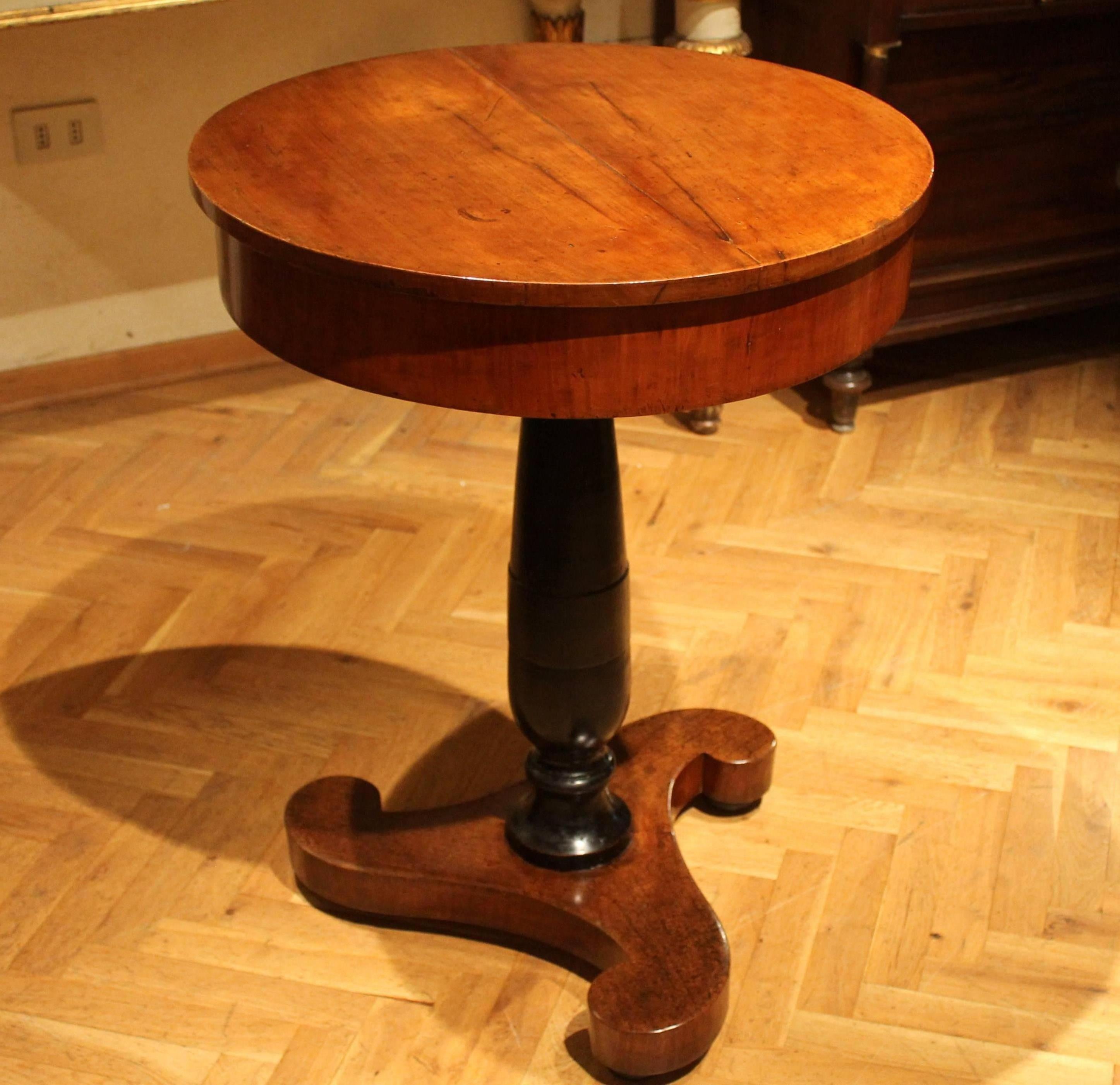 This beautiful antique early 19th century Italian empire circular center table in blonde flamed walnut wood and black ebonized wood comes from a villa in Tuscan countryside. This is a very good quality side table with circular top sitting above a