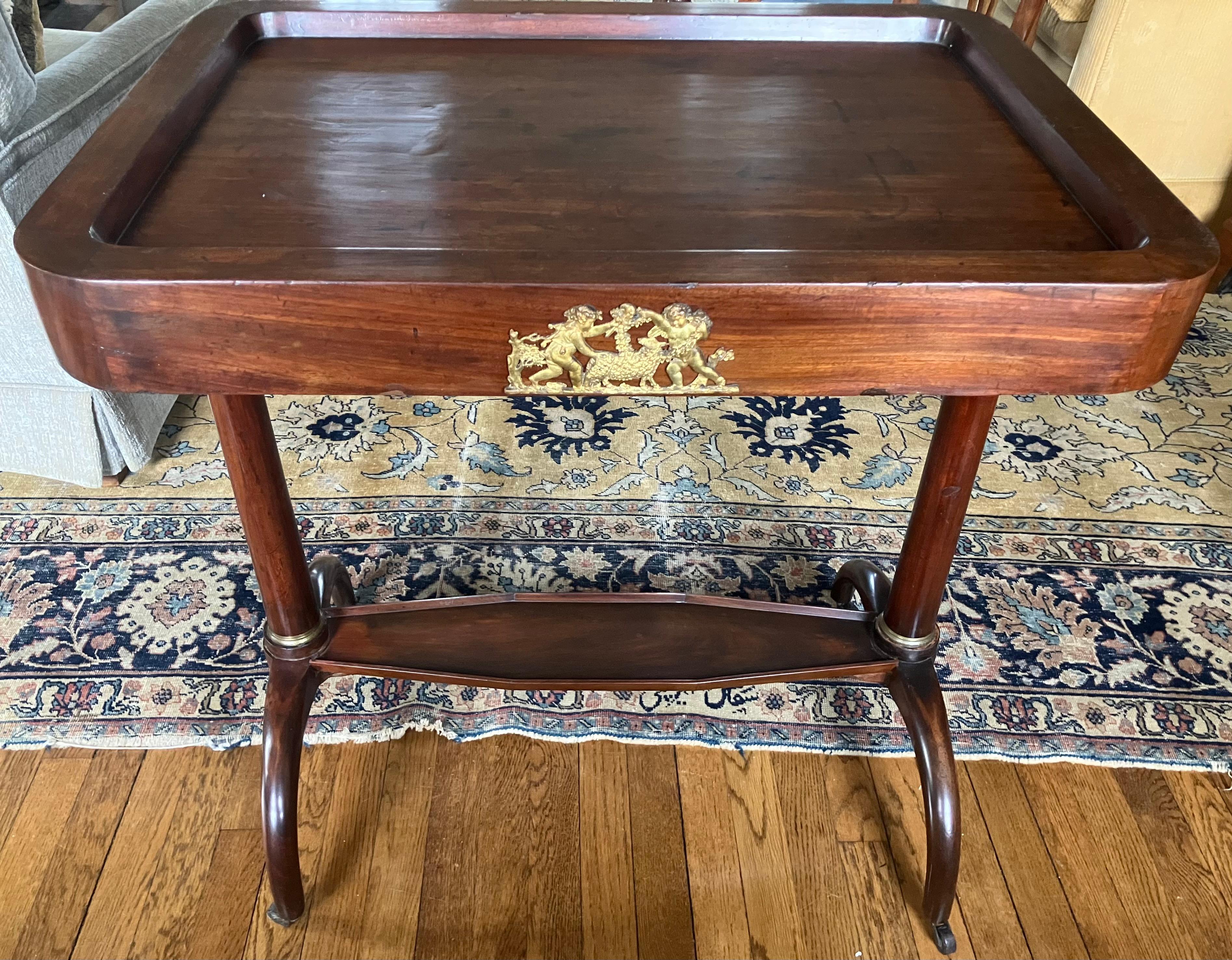 Tavolo da portata del periodo Impero italiano. Carrello di servizio in mogano del periodo Impero napoletano con ampia area di servizio incassata per il servizio di piatti o bar con scena carnevalesca ormeggiata di putti e agnello inghirlandato,