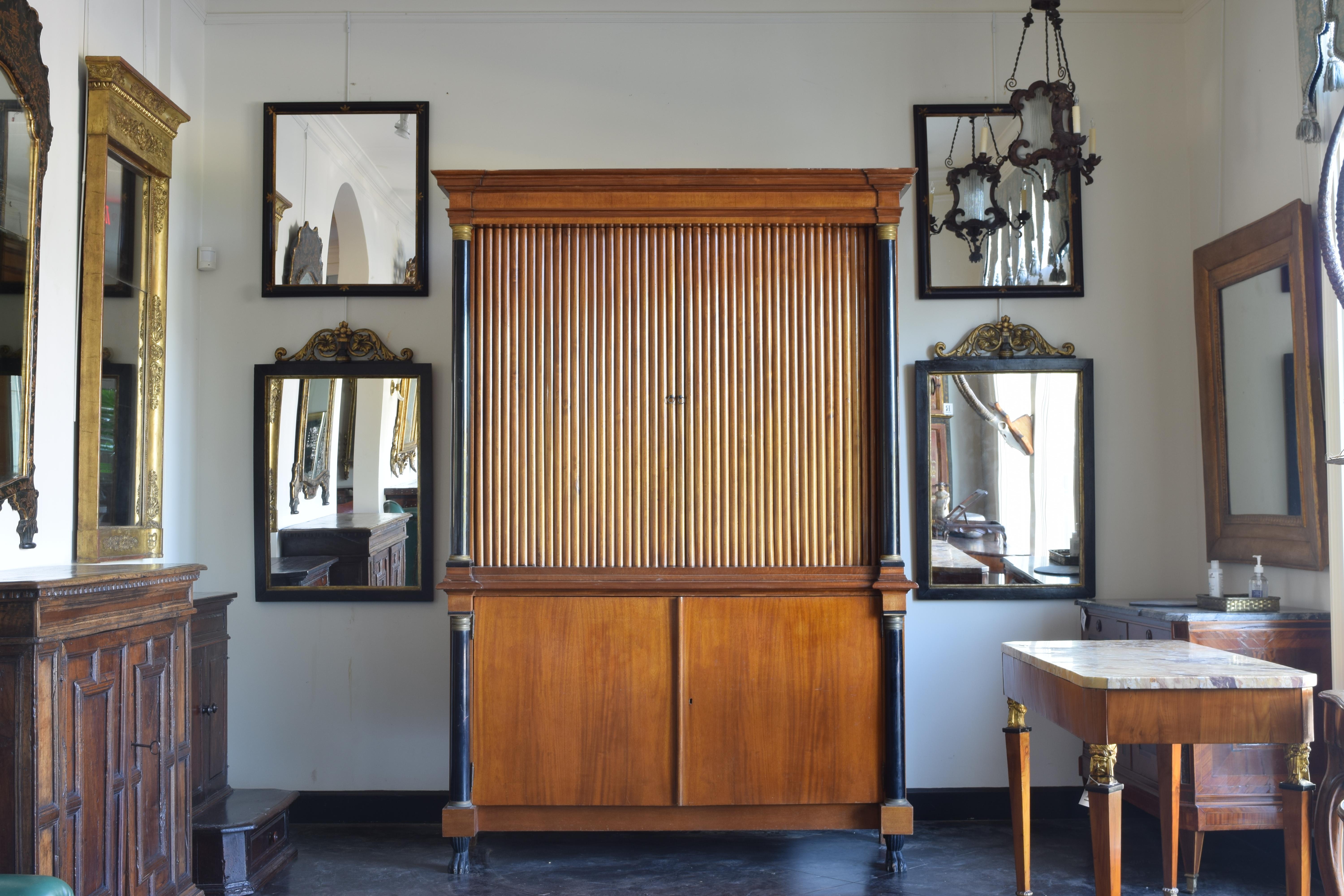 Handsomely styled with ebonized columns on both sides of the fluted cabinet. Raised on a 2 door case with an interior shelf ending on ebonized and carved paw feet in the front, block feet in the back.