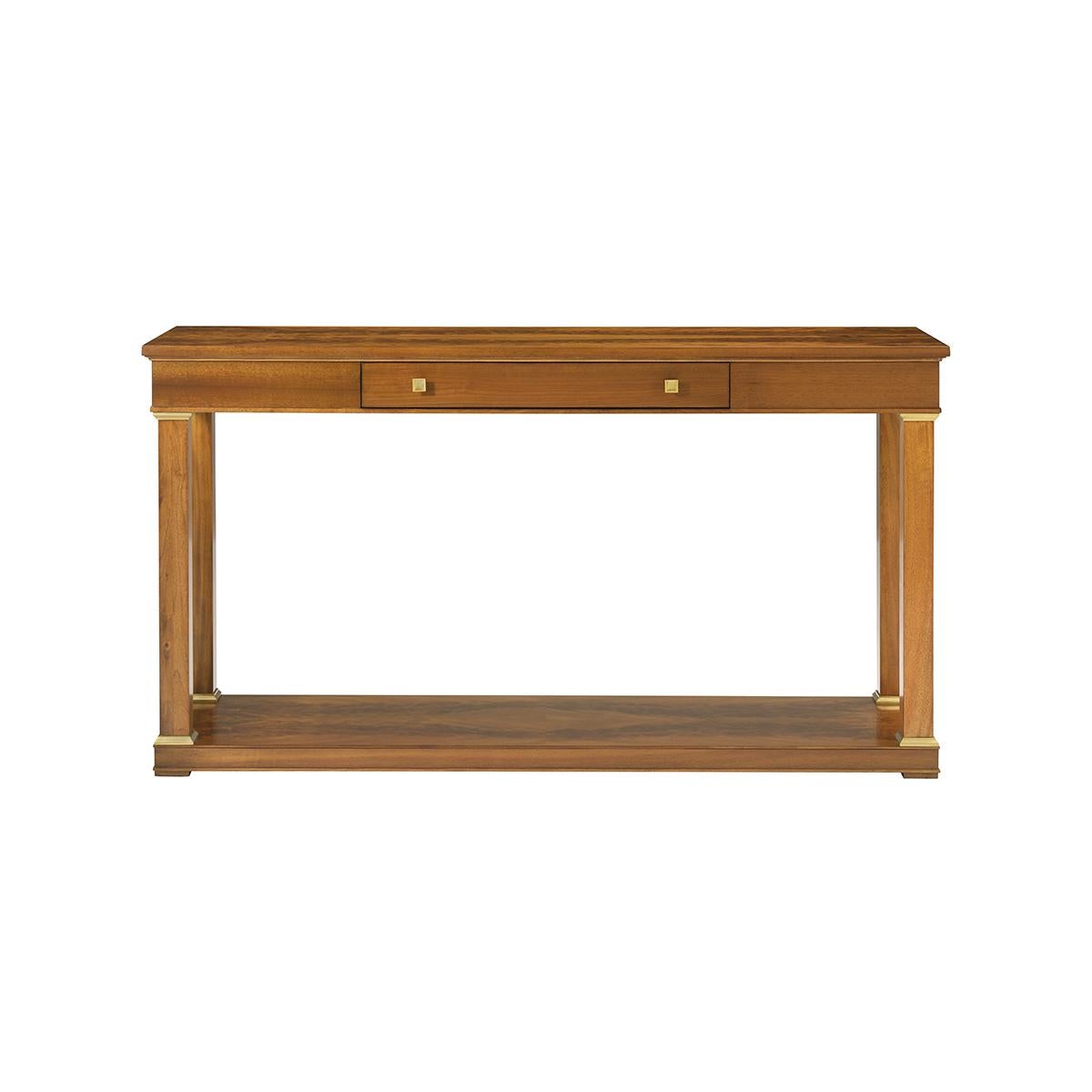 A sophisticated Neoclassical design, with strict pilaster legs with brass trimmings. A veneered top and apron with a drawer sit atop a tall open space meant to accommodate accessories on a veneered lower base.

Dimensions: 60