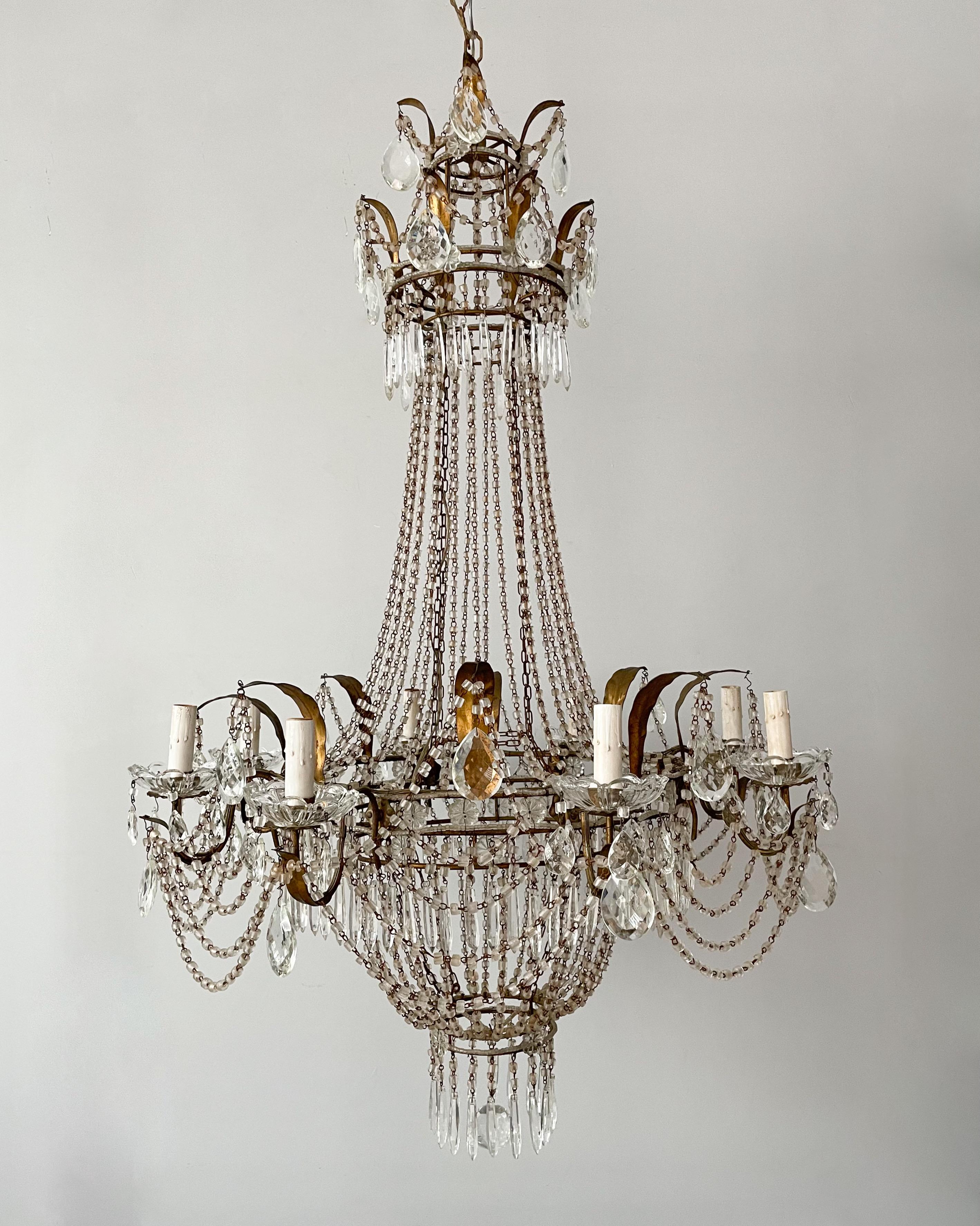 Gorgeous, 1940s Italian crystal beaded
chandelier in the Empire style.

The chandelier consists of a leafy gilt iron
frame decorated with cascading macaroni glass beads and faceted prisms. The beads have acquired a pleasing rusty patina over the