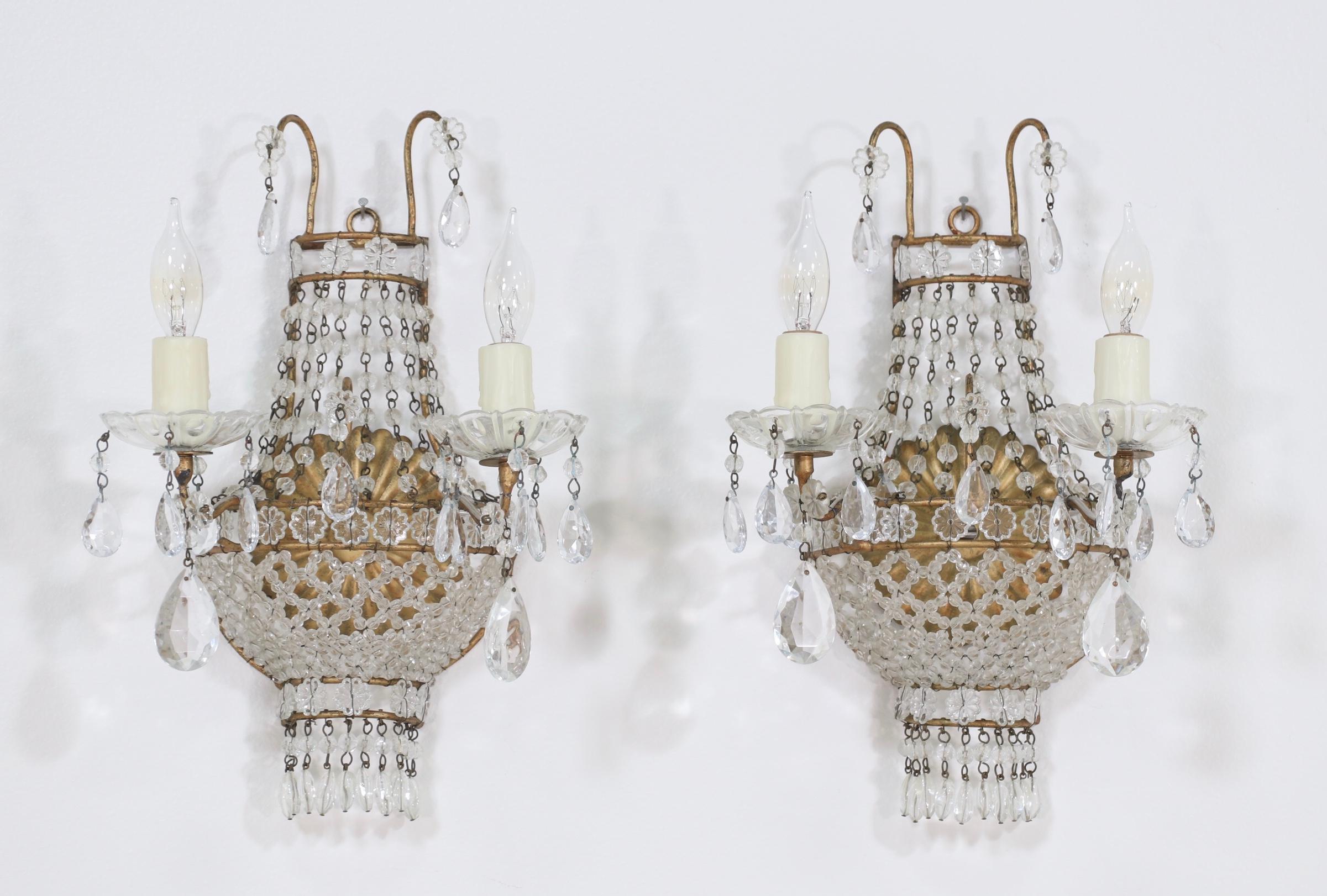 Gorgeous, 1940s Italian gilt-iron and crystal beaded sconces in the Empire style.

These petite-scale beauties feature a gilt iron frame with delicately weaved crystal beaded bases, crystal boebeches and faceted prisms. The sconces are wired and