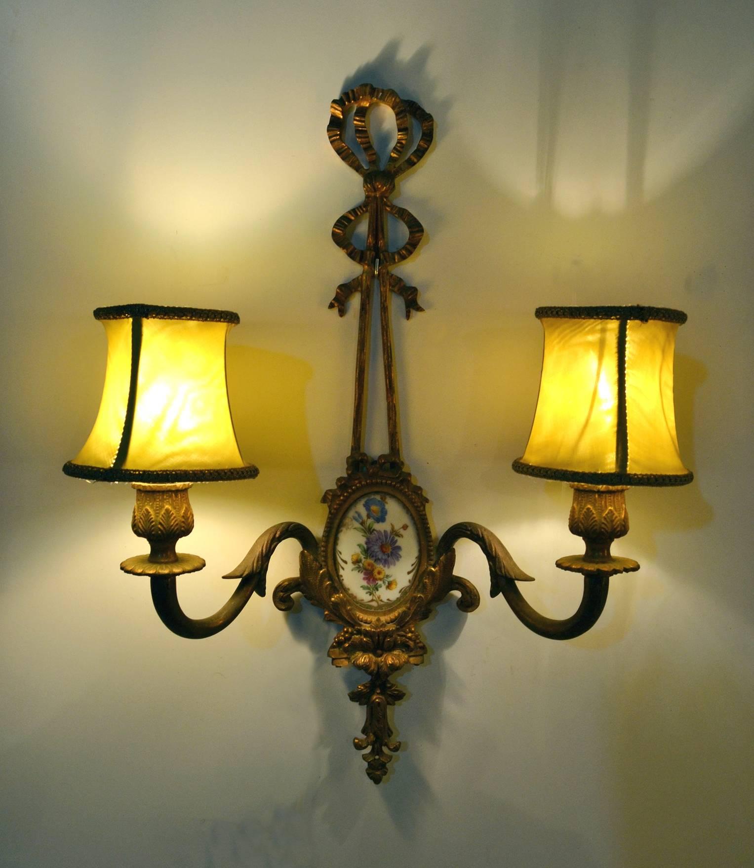 Vergoldete Wandleuchter im Empire-Stil in Form von Bändern aus massiver Bronze mit eingelegtem, handbemaltem Porzellandekor. Produziert in den 1950er Jahren. Wird mit lindgrünen Lampenschirmen geliefert. Geeignet für E14-Glühbirnen.