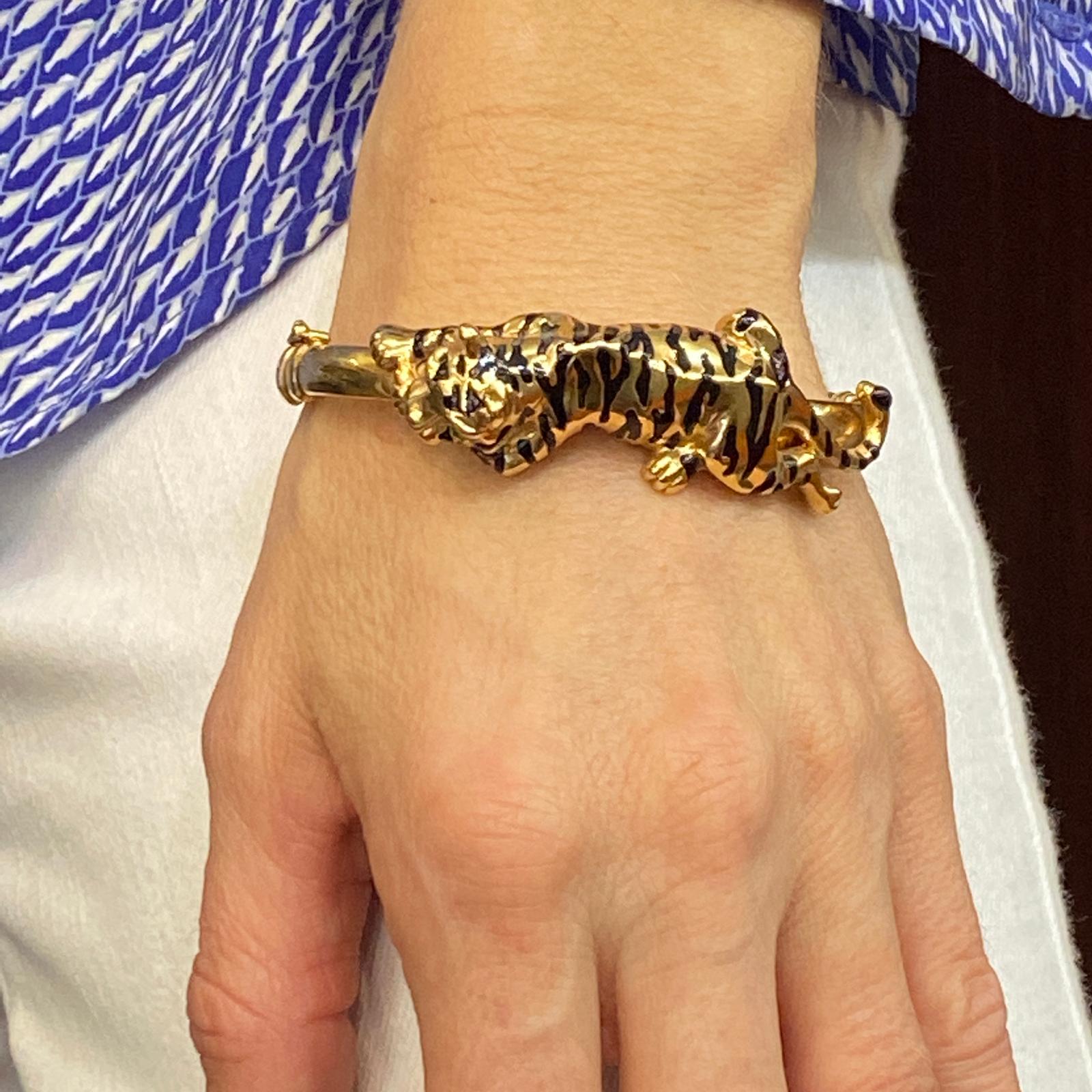 Italian enamel tiger bangle bracelet fashioned in 14 karat yellow gold. The hinged bangle features a black enamel tiger with emerald eyes. The tiger measures 20mm in width, and the bracelet measures 7 inches in circumference. 