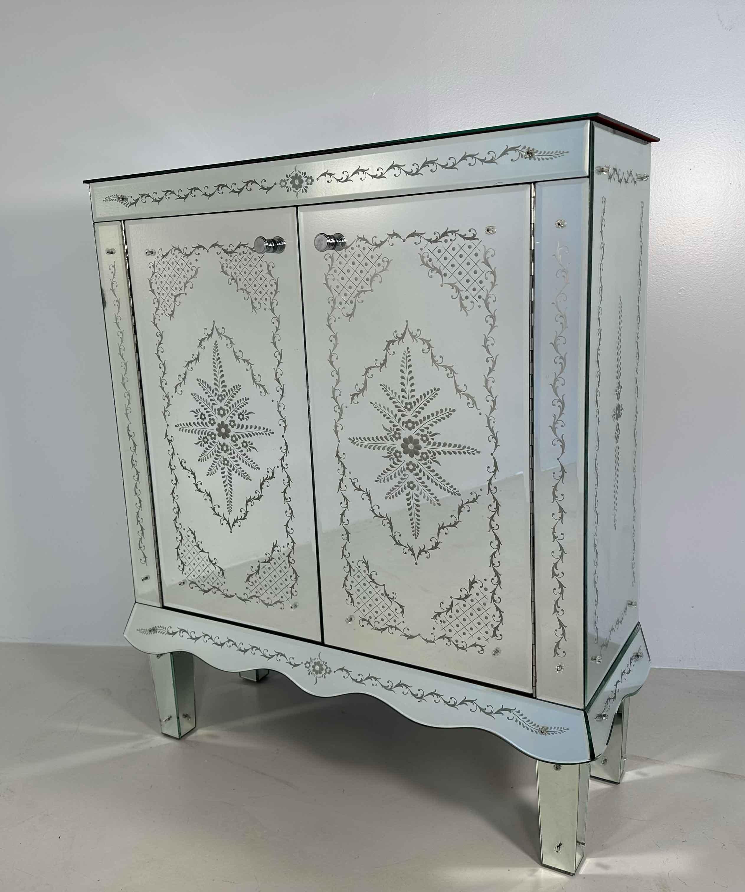 This Art Deco style Cabinet was produced in Italy in the 1980s circa. 
It is completely covered of Murano Glass bevelled panels. The real star of this piece is her majesty the engraving. The patterns on the mirrors, obtained by means of its grinding