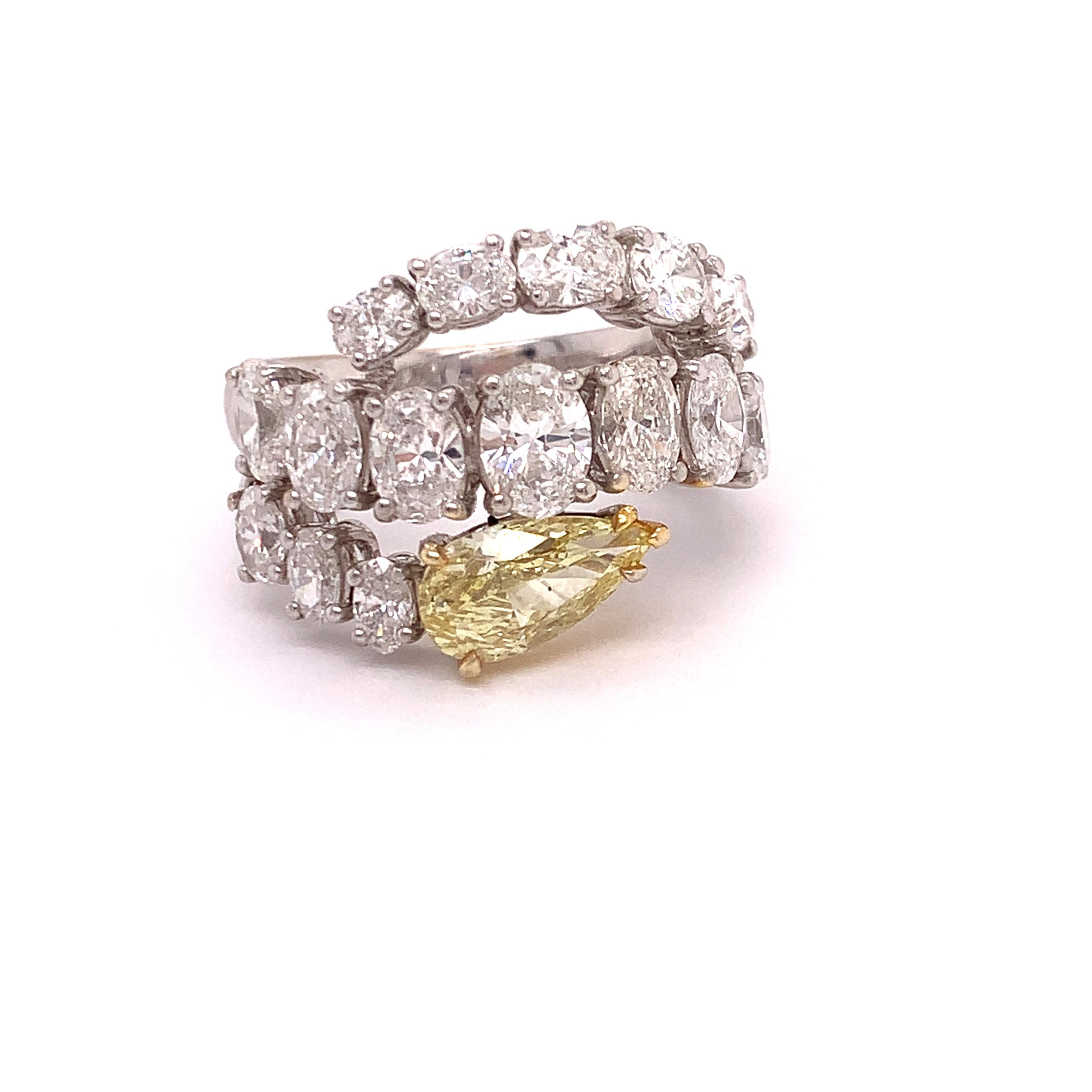 This one of a kind high fashion diamond ring features a 1.79 carat pear shape fancy yellow diamond with SI2 clarity. There are seventeen beautiful oval cut diamonds weighing 3.53 cttw.  They are F color and VVS Clarity.  This is set in 18Kt white