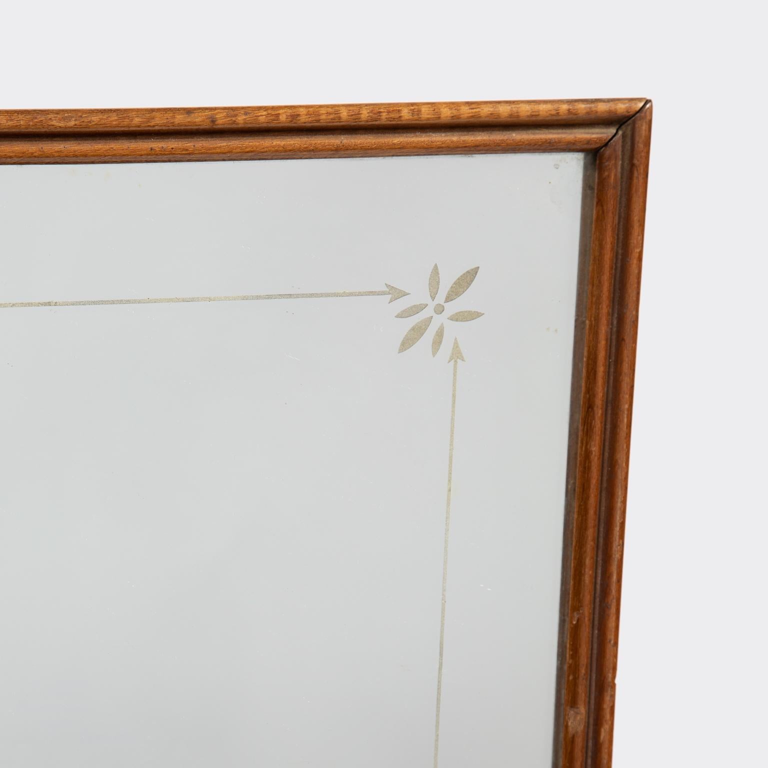 Slim mahogany frame mirror, with notch shaped top, and mirror glass with a delicate etched floral and arrow motif border.