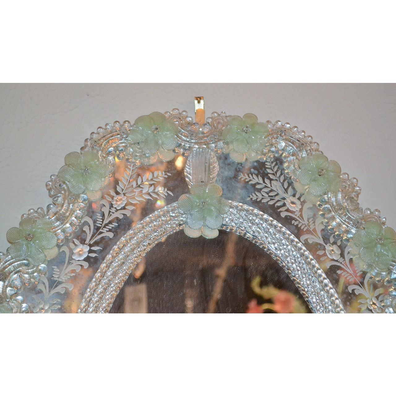 Beautifully elegant antique Italian Venetian glass oval mirror. The shaped beaded border accented with leaf scrolls and greenish hue rosettes outside an etched glass band featuring leaf sprays and flower heads,

circa 1900.