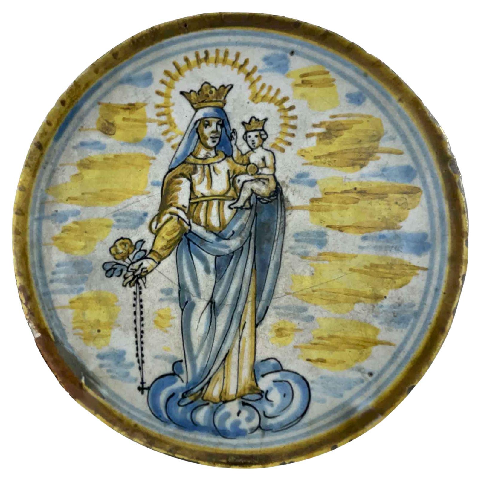 From Central Italy a 18th Century Majolica Riser consisting of a flat circular dish with raised edge, resting on a base with a simple shape. The top has a polychrome decoration, mainly in yellow and blue colors, depicting the Madonna with