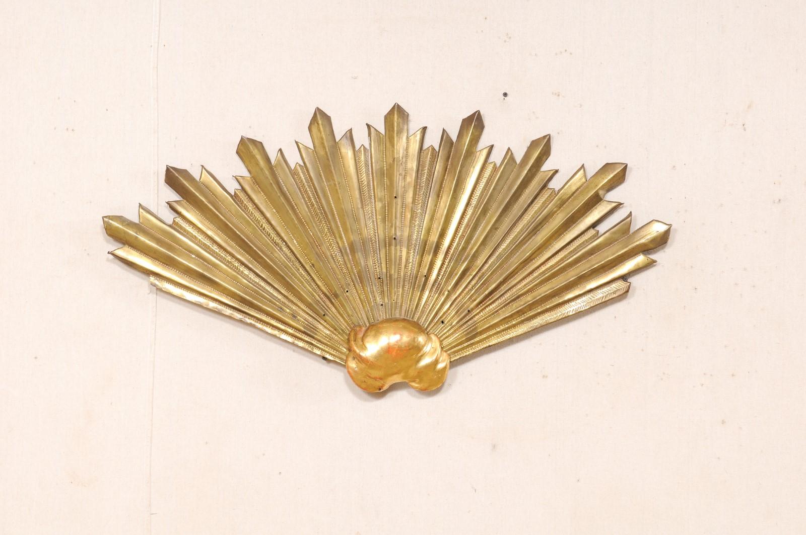 An Italian wall decoration of brass and gilt sun-rays from the 19th century. This antique ornament from Italy features a wooden cloud (which retains its original gilt finish) at bottom, from which a fan-shaped formation of brass sun-rays emerges up