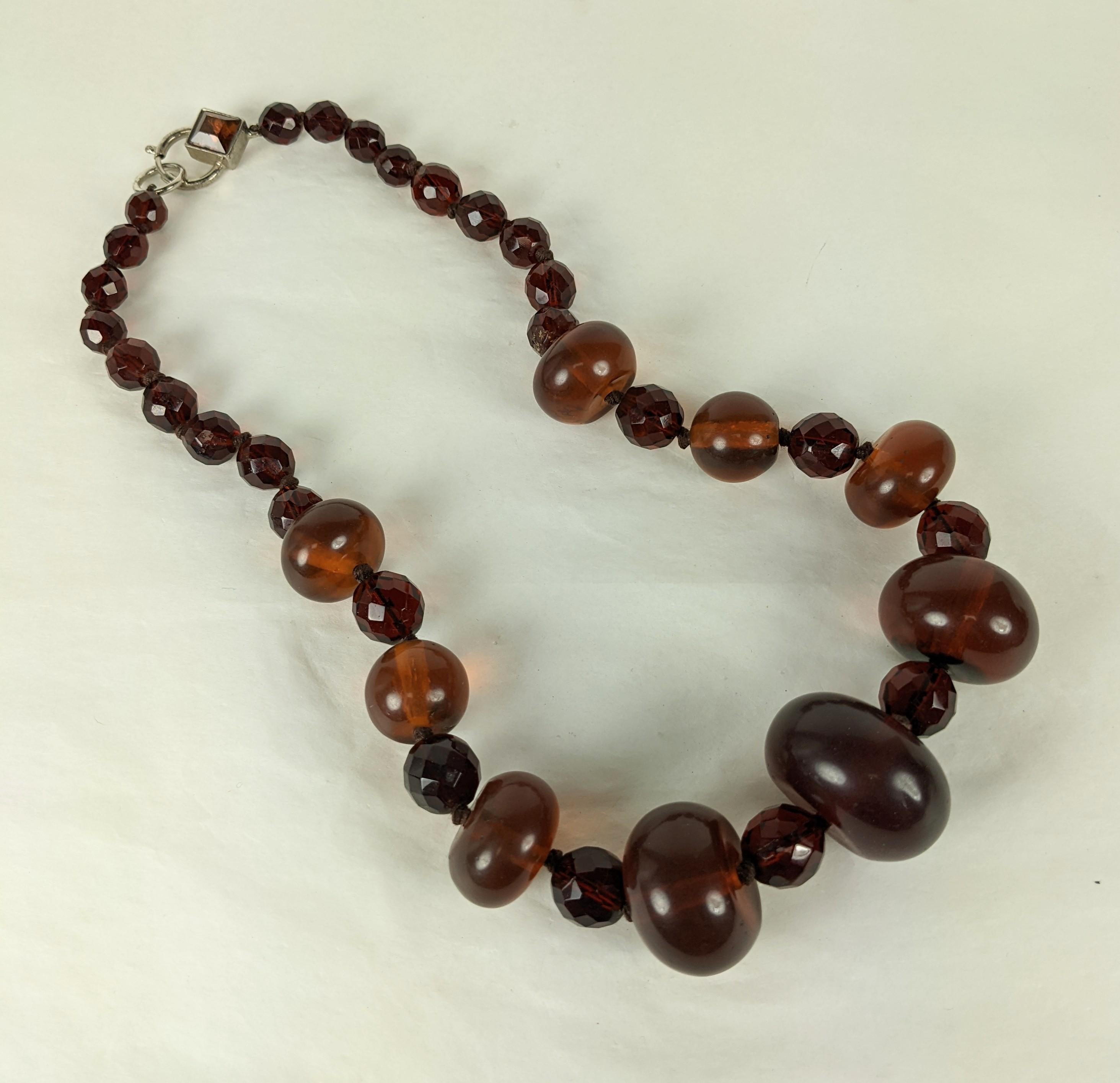 Superbe collier italien en fausses perles d'ambre datant des années 1980. L'Italie est connue pour ses magnifiques bijoux en résine et en bakélite. Il y a des perles de différentes tailles avec des entretoises à facettes qui sont nouées à la main