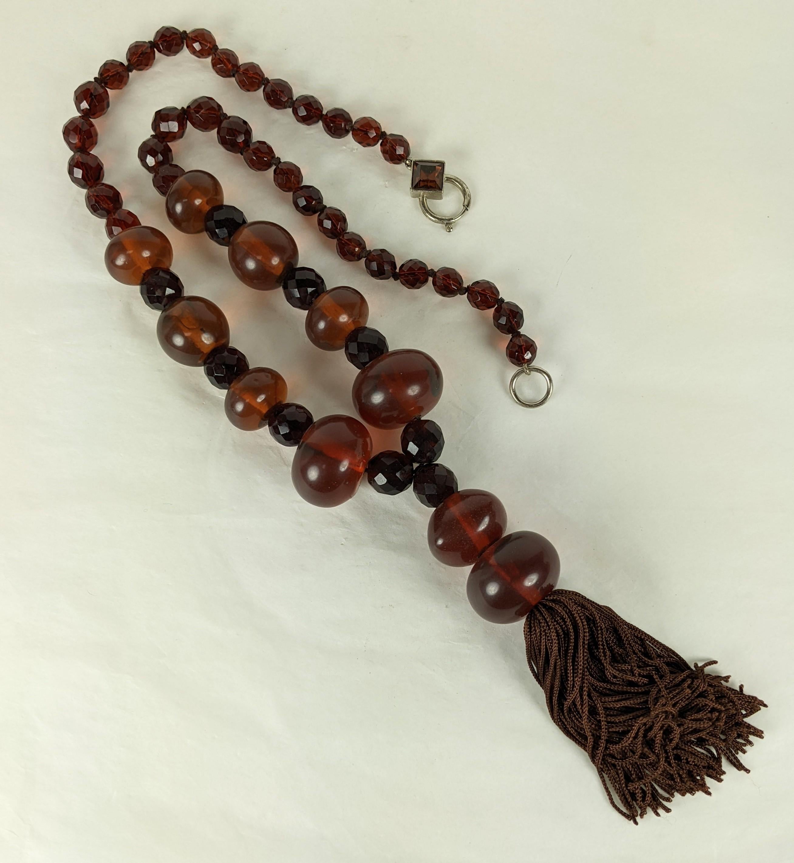 Striking Italian Faux Amber Tassel Bead Necklace from the 1980's. Italy is known for its amazing resin and bakelite jewelry. There are different sized beads with faceted bead spacers which are hand knotted with jewel crystal clasp and large silk