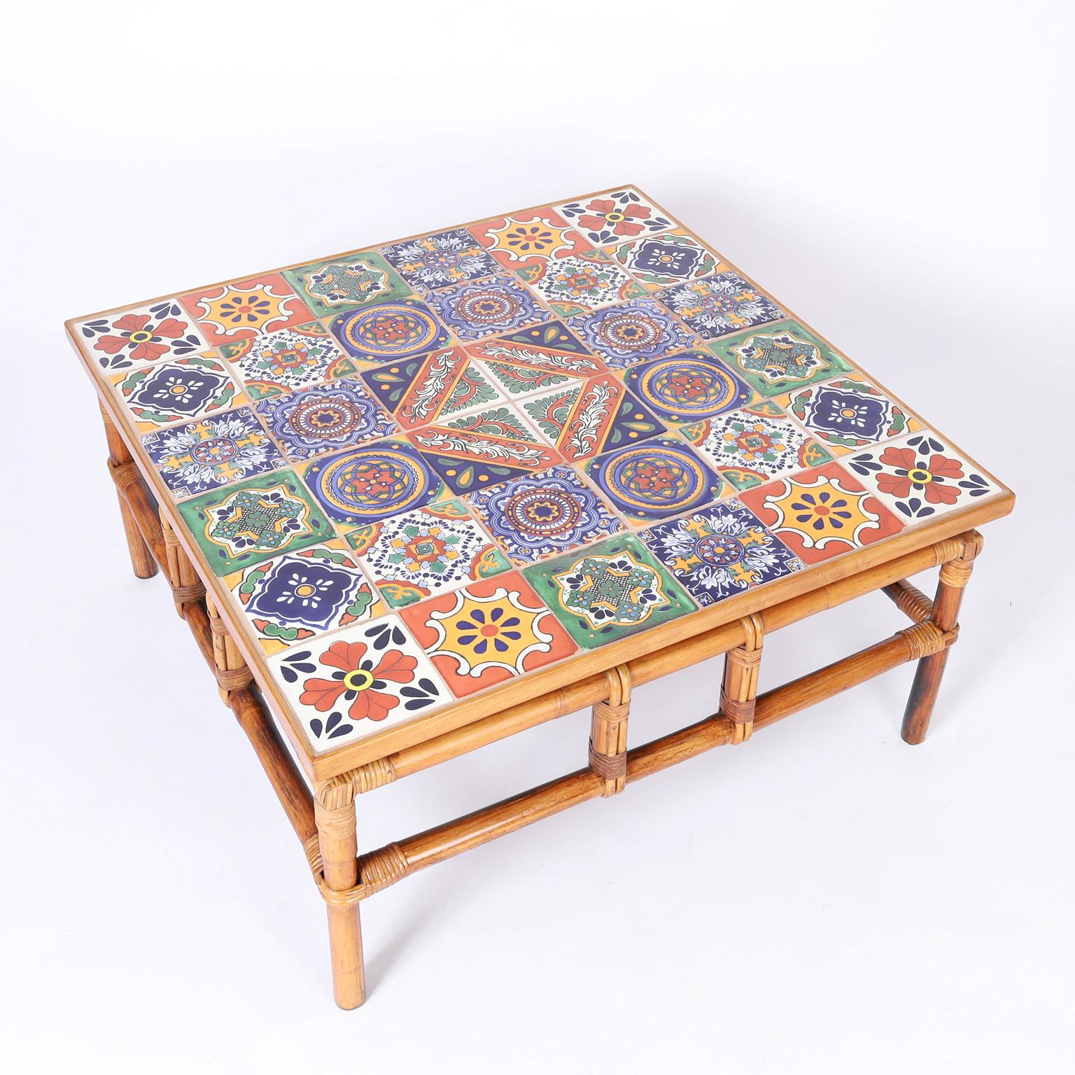 Mid century coffee table with distinctive Italian colorful ceramic tiles on the top over a faux bamboo frame with reed wrapped highlights. Possibly by McGuire.