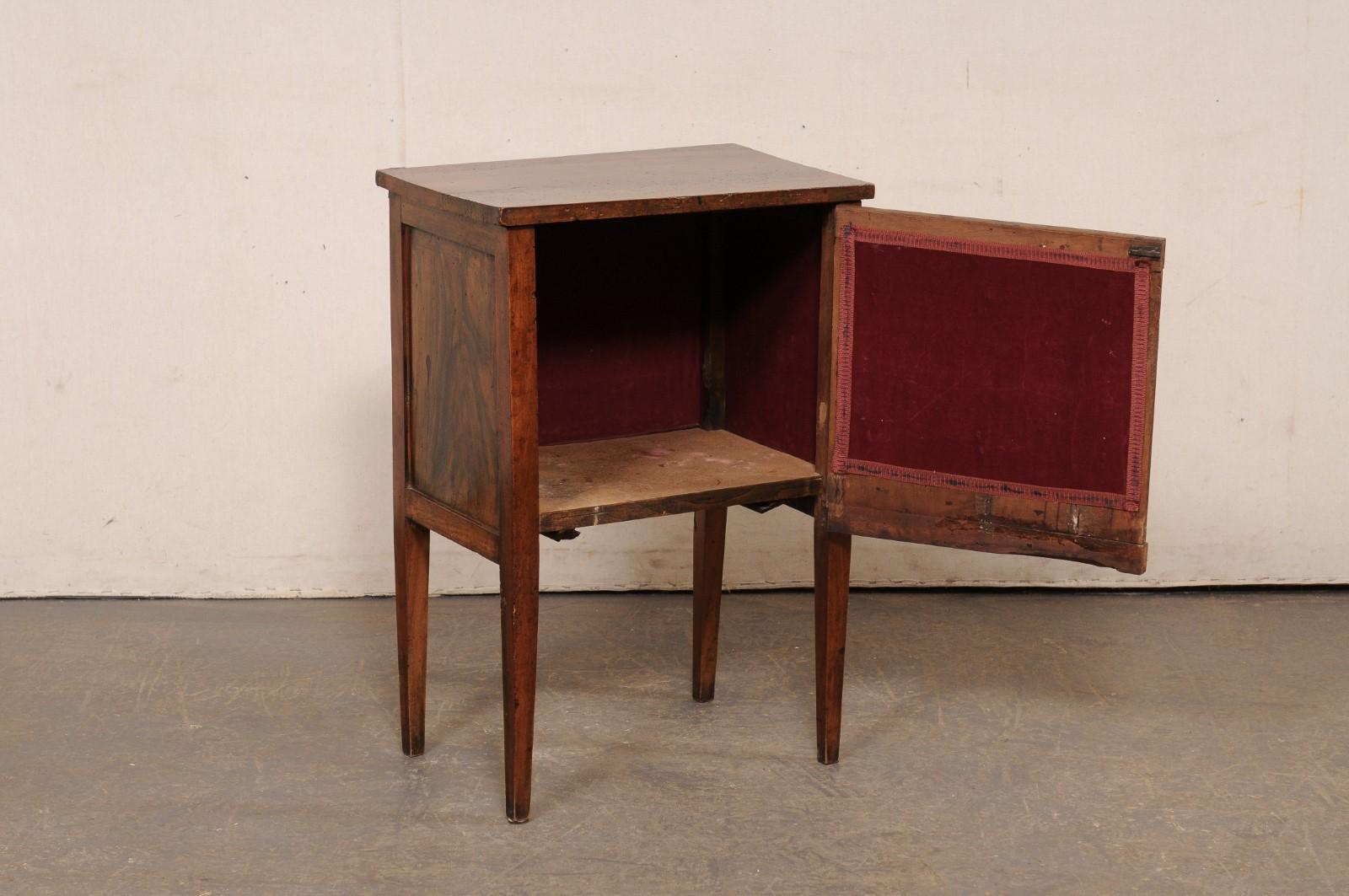 An Italian wooden raised side chest, with faux-drawer design and lift-top storage, from the early 19th century. This antique side chest or end-table from Italy, circa 1800, features nice clean lines, recessed panel sides, a center door with a two
