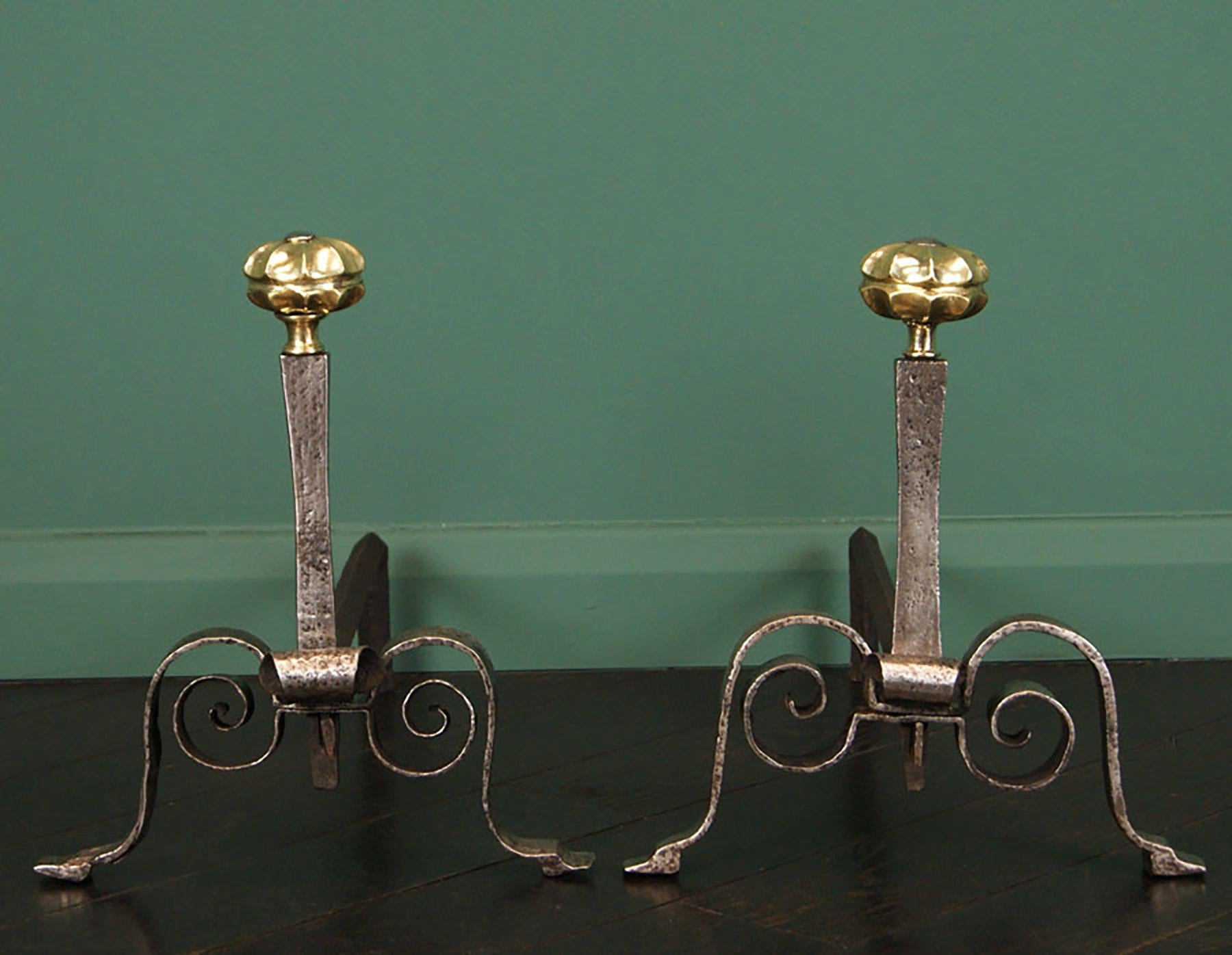 A delicately crafted pair of fine 18th century Italian wrought and gun-metal fireplace andirons. Scrolled, arched feet with wedge-pin locking all elements in position. Segmented gun-metal finials uppermost. Historical repair to one foot.