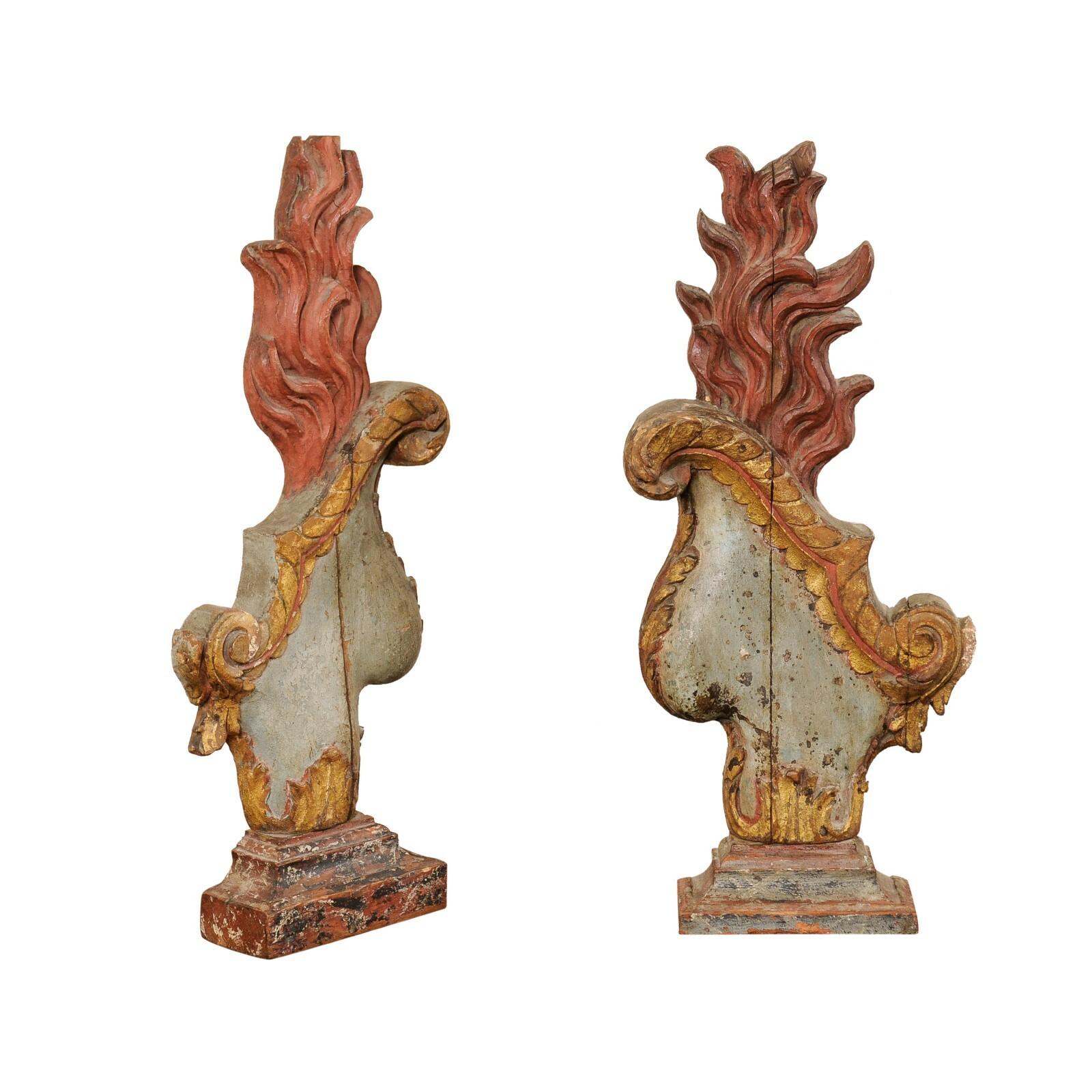 A pair of Italian hand-carved and painted wood fragment wall or table decorations. These fabulous fragment ornaments from Italy each feature a carved urn, with harp-shaped body embellished adorned in volutes and foliate, with flames rising out of