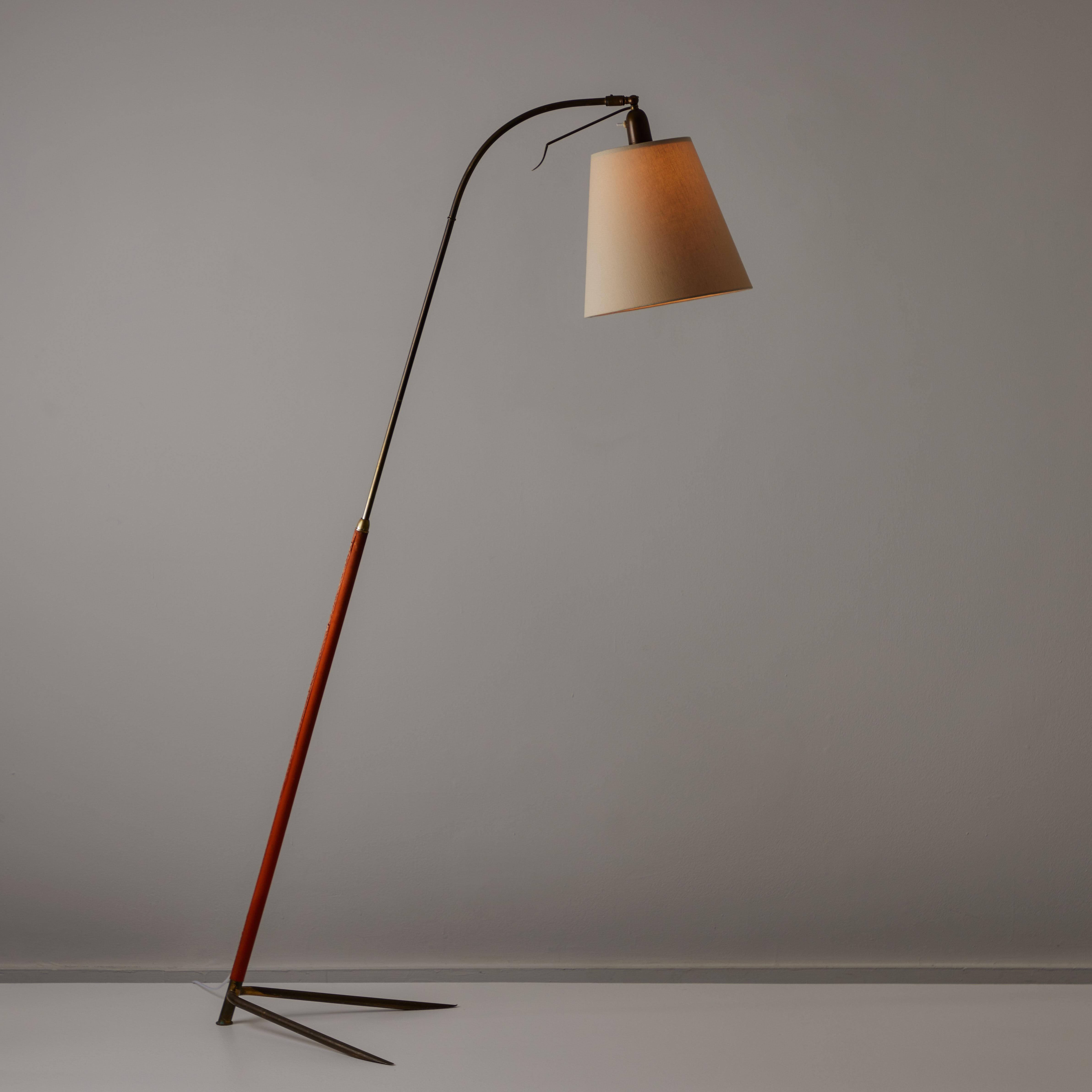 Italian Floor Lamp. Designed and manufactured in Italy, circa the 1950s. This detailed floor lamp features an orange leather wrapped detail on the brass stem and a linen shade. The lamp shade can be articulated in and outward with the brass control