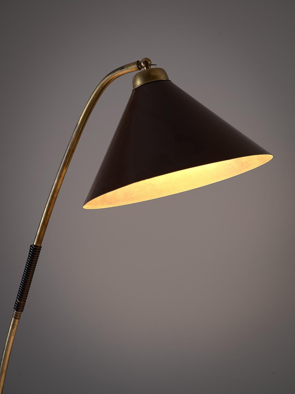 Floor light, in brass and metal, Italy, 1950s. 

Elegant floor light with an elegant brass leg. The brass stern is elegantly shaped and forms the base of the light. The brass foot holds the leg that is attached in a playful way. The shade is built