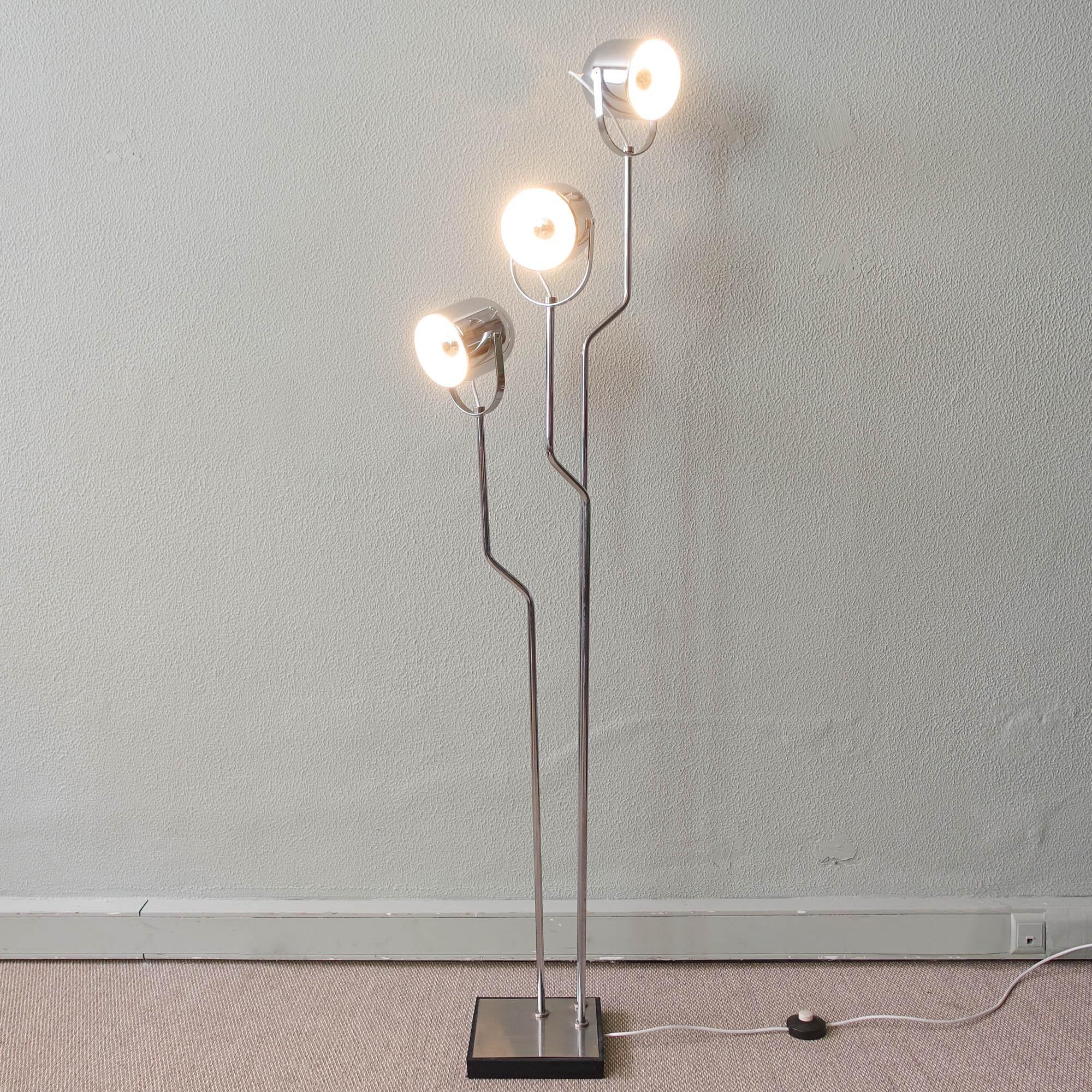 This floor lamp was designed by Goffredo Reggiani for Reggiani, in Italy, during the 1970s. It is a chromed-steel floor lamp that features three fully adjustable fixtures affixed to a corresponding chromed-steel bent rod. The spot lights in