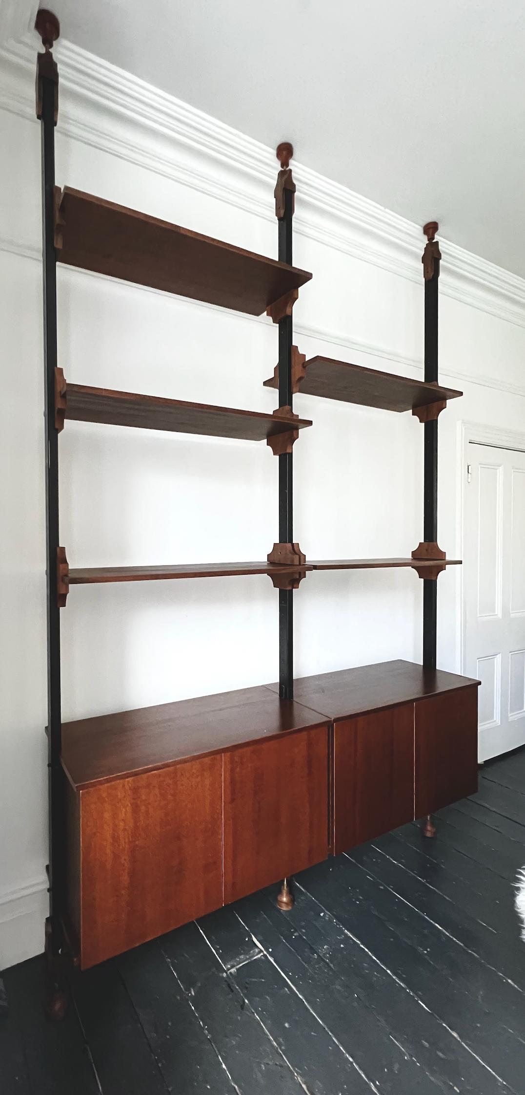 A floor-to-ceiling shelving unit, with space for both display and storage. Italy, second half 20th century. Designer unknown.

The set is made of wood, finished in walnut, with black metal uprights running between the floor and ceiling. The larger