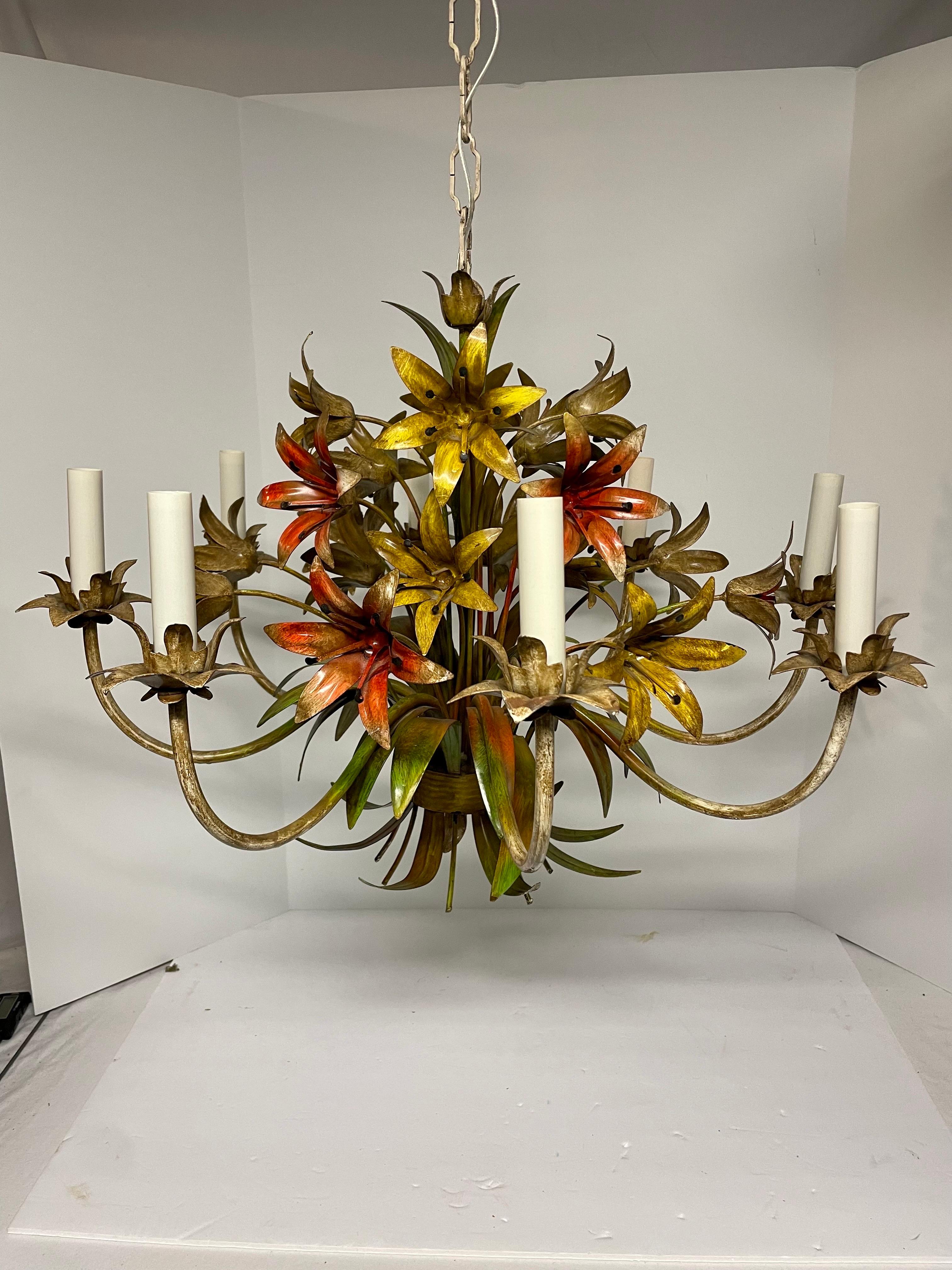 Large scale Italian floral tole six arm chandelier. Lots of  Lilly flowers in yellows and reds with greens and cream. Some chipping paint that adds to the character. Rewired. and in good working condition. Measures: 26
