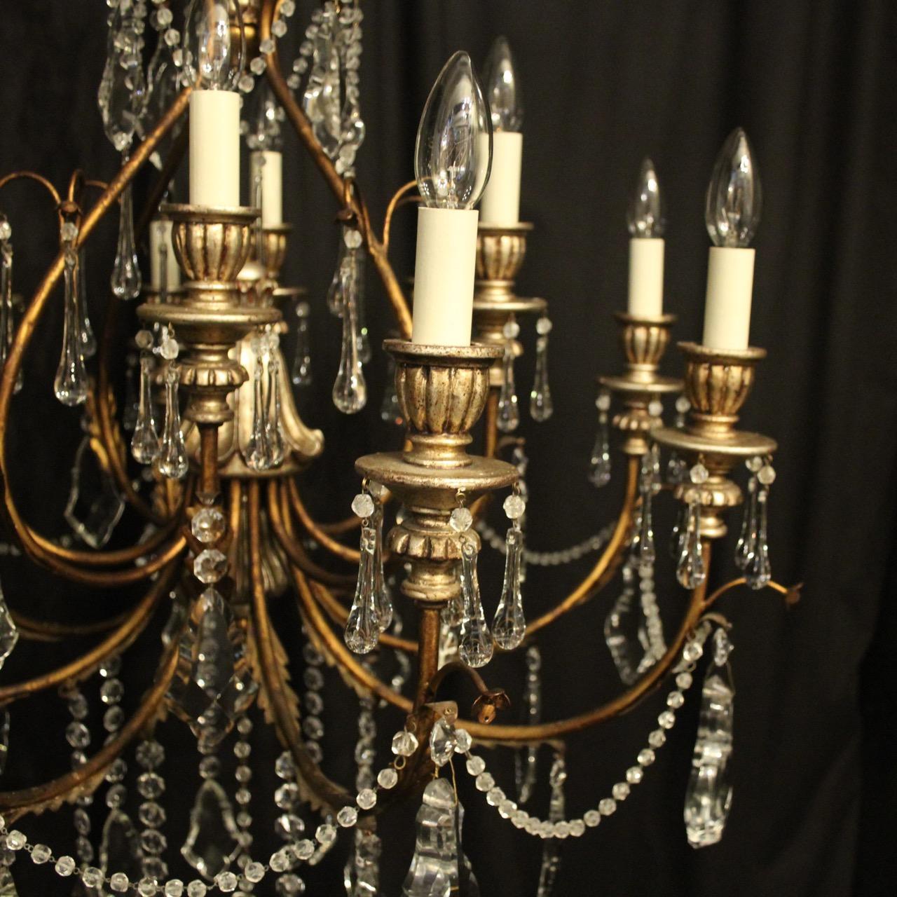 A decorative large Italian Florentine wooden silver polychrome and crystal 12-light double tiered chandelier, the Acanthus metal leaf scrolling arms with carved wooden reeded bulbous candle sconces, issuing from an elaborate open cage central column