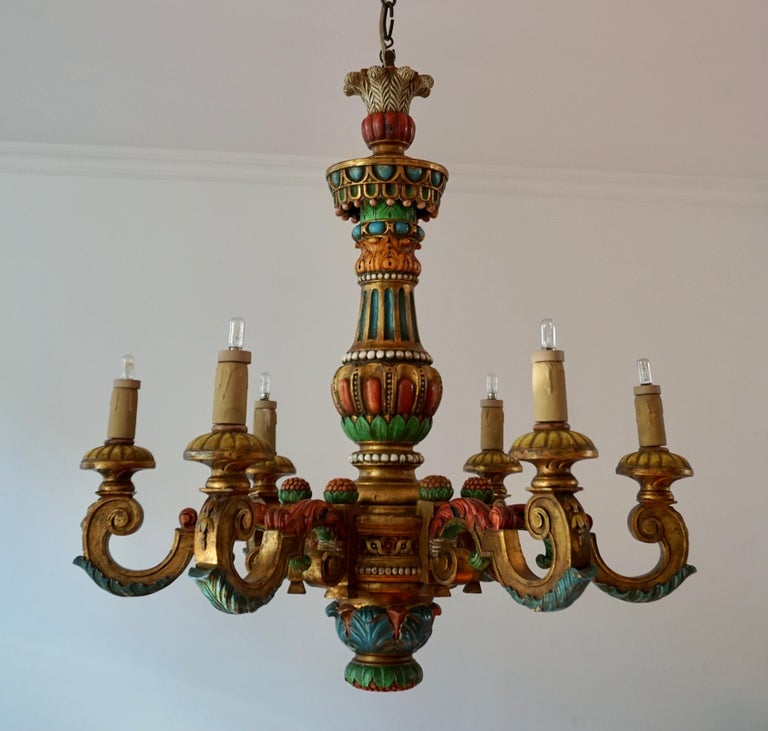 A beautiful chandelier with six lights that was made in the Italian region of Florence, circa 1950. The chandelier is made in polychrome hand carved wood. The chandelier feature C-scrolls acanthus and other Baroque motifs. The color combination of