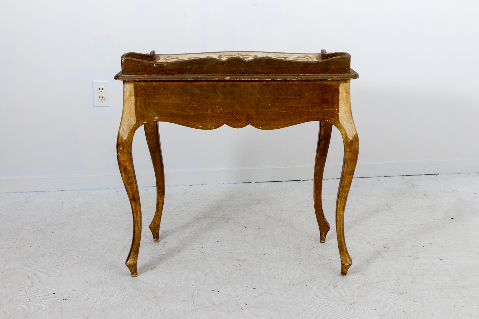 Italian Florentine Louis XV style gilded and painted desk, vanity, or console, circa 1950s. The piece features painted motifs of scrolled foliage and cabriole legs. Made in Italy. Please note of wear consistent with age including paint loss, gilt