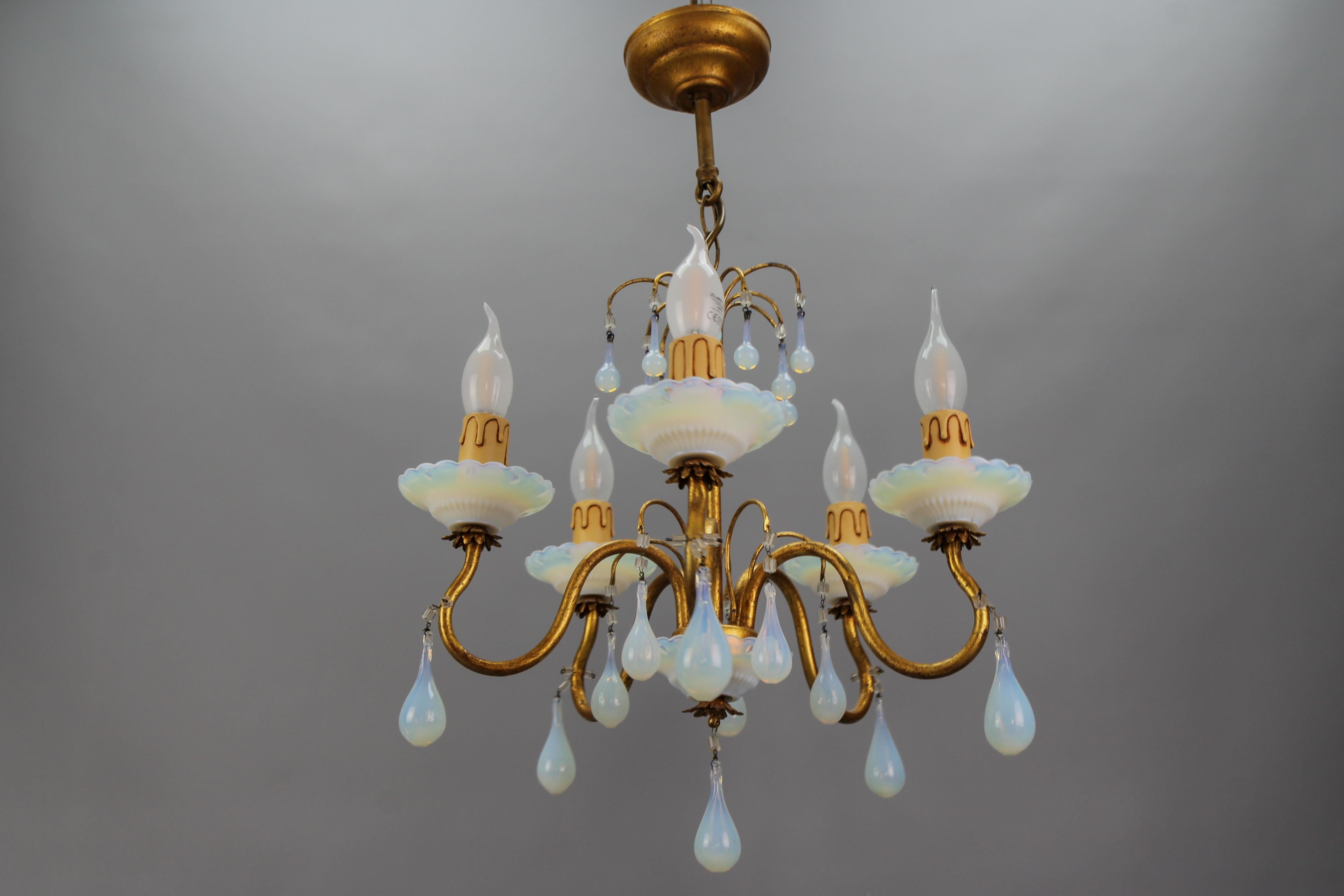 Italian Florentine gilt metal and white opalescent glass five-light chandelier.
This adorable Hollywood Regency-style chandelier features five chandelier arms each with a white opalescent glass bobeche and a socket for an E14 Size light bulb. The