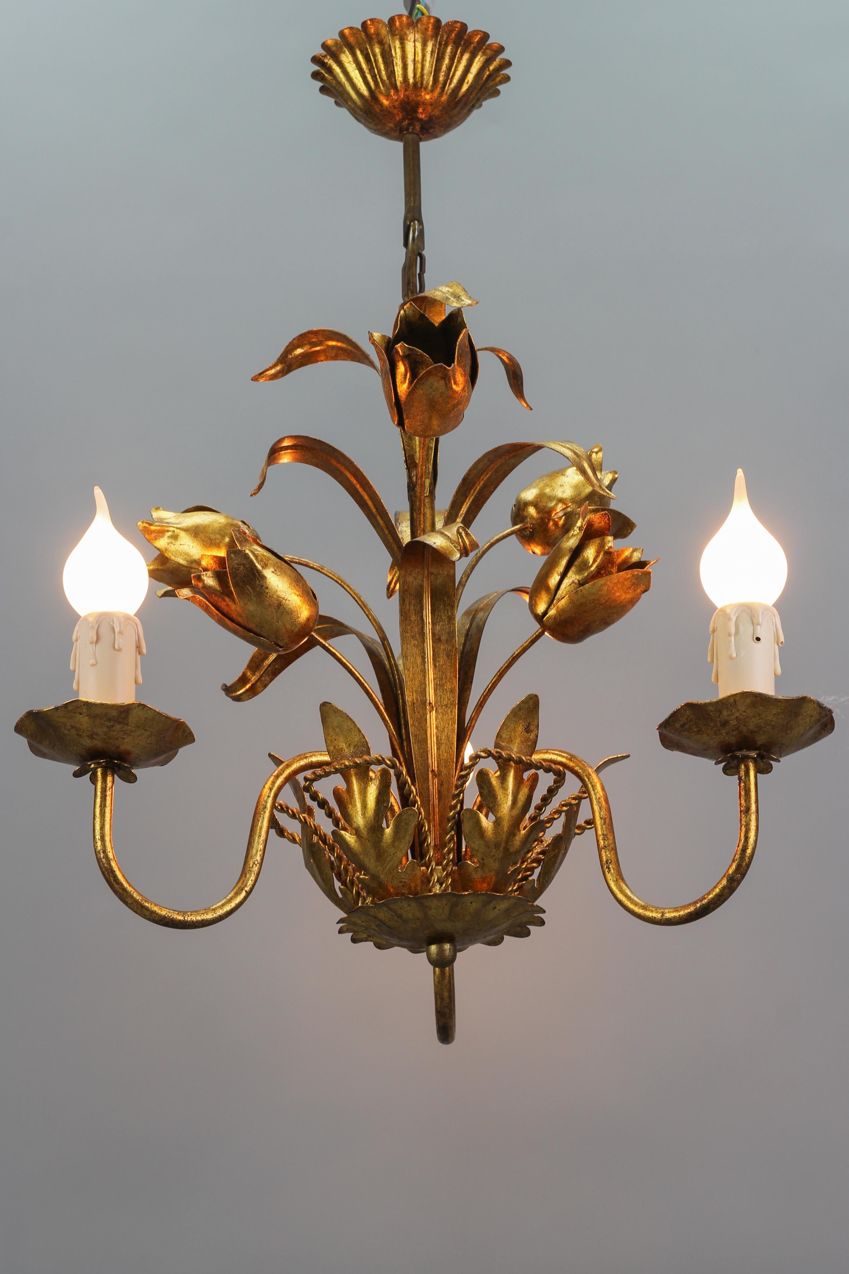 A beautiful Italian gilt metal/toleware three-light chandelier from the 1970s. The golden light fixture is adorned with charming flowers - tulips and leaves. 
Three sockets for E14 size light bulbs.
Dimensions: height: 55 cm / 21.65 in; diameter: