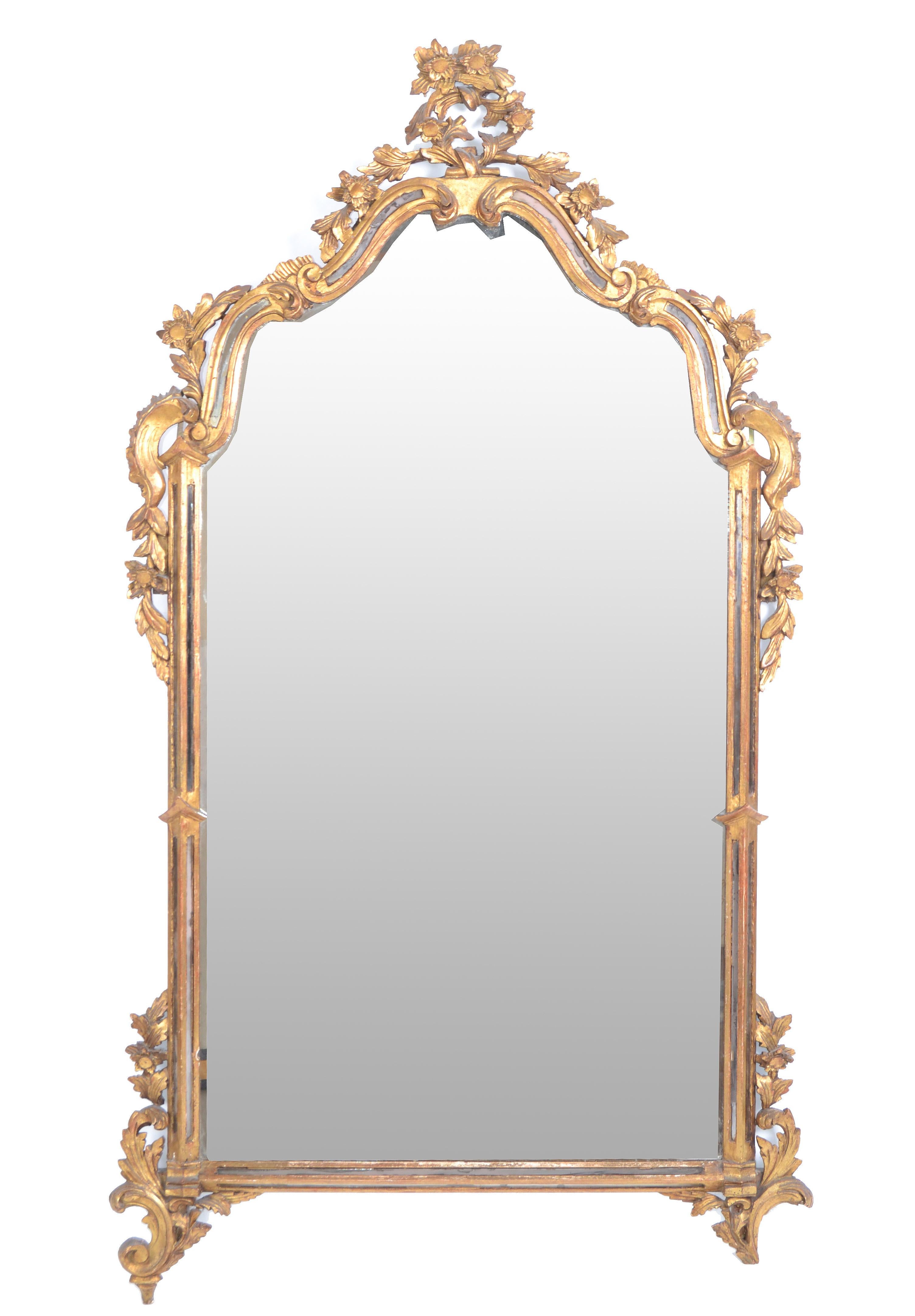 Hand carved Florentine giltwood and antique mirrored glass wall mirror, made in Italy.
The mirror is in original condition and shows foxing which adds character to the old treasure.
Wooden backing supports a secure way of hanging it.