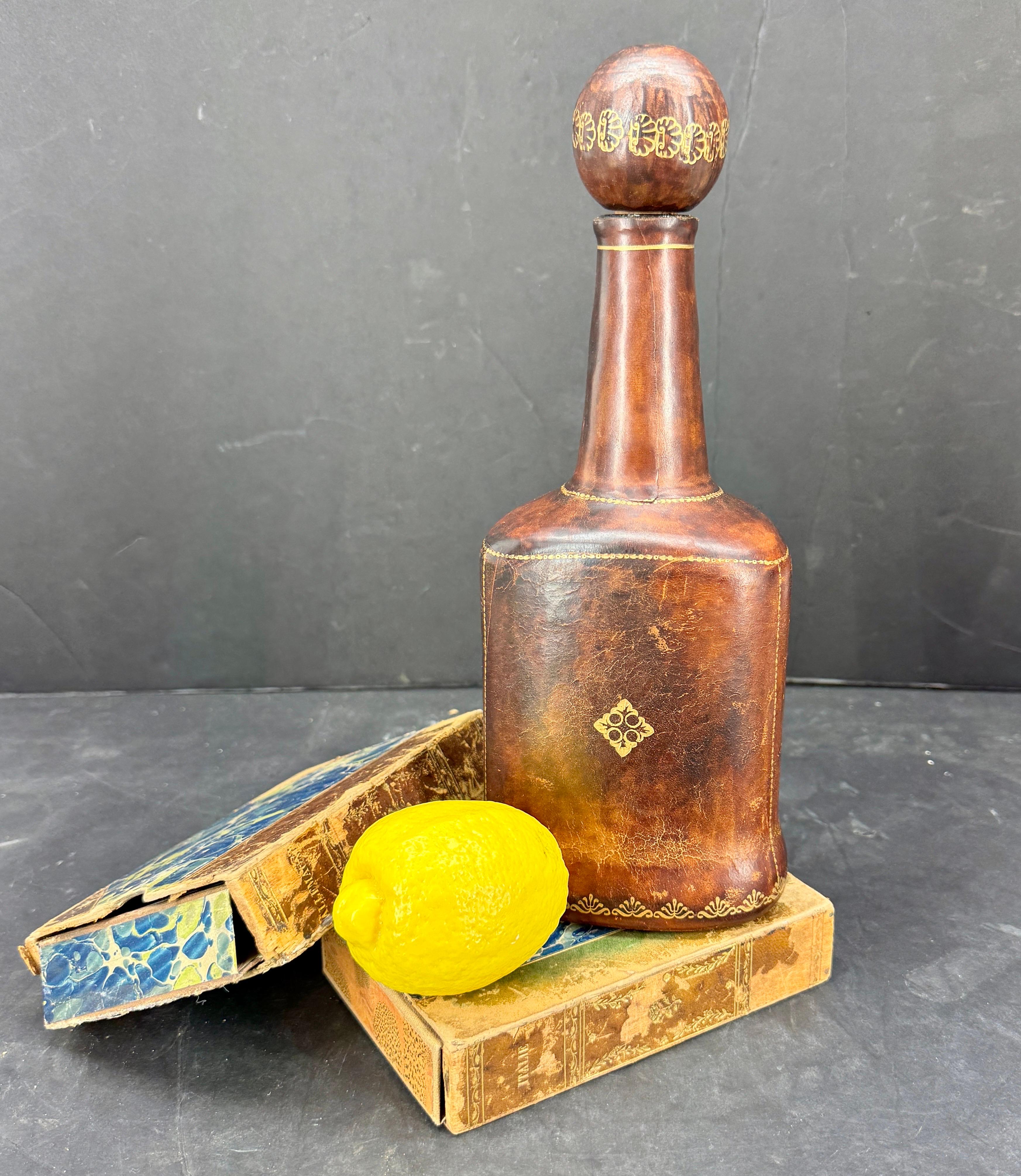 Licorera florentina de cuero y cristal de Italia. Esta impresionante pieza florentina presenta una deseable e inmejorable pátina tanto en la propia botella como en el tapón de bola. Maravillosa pieza única para añadir a cualquier colección o para