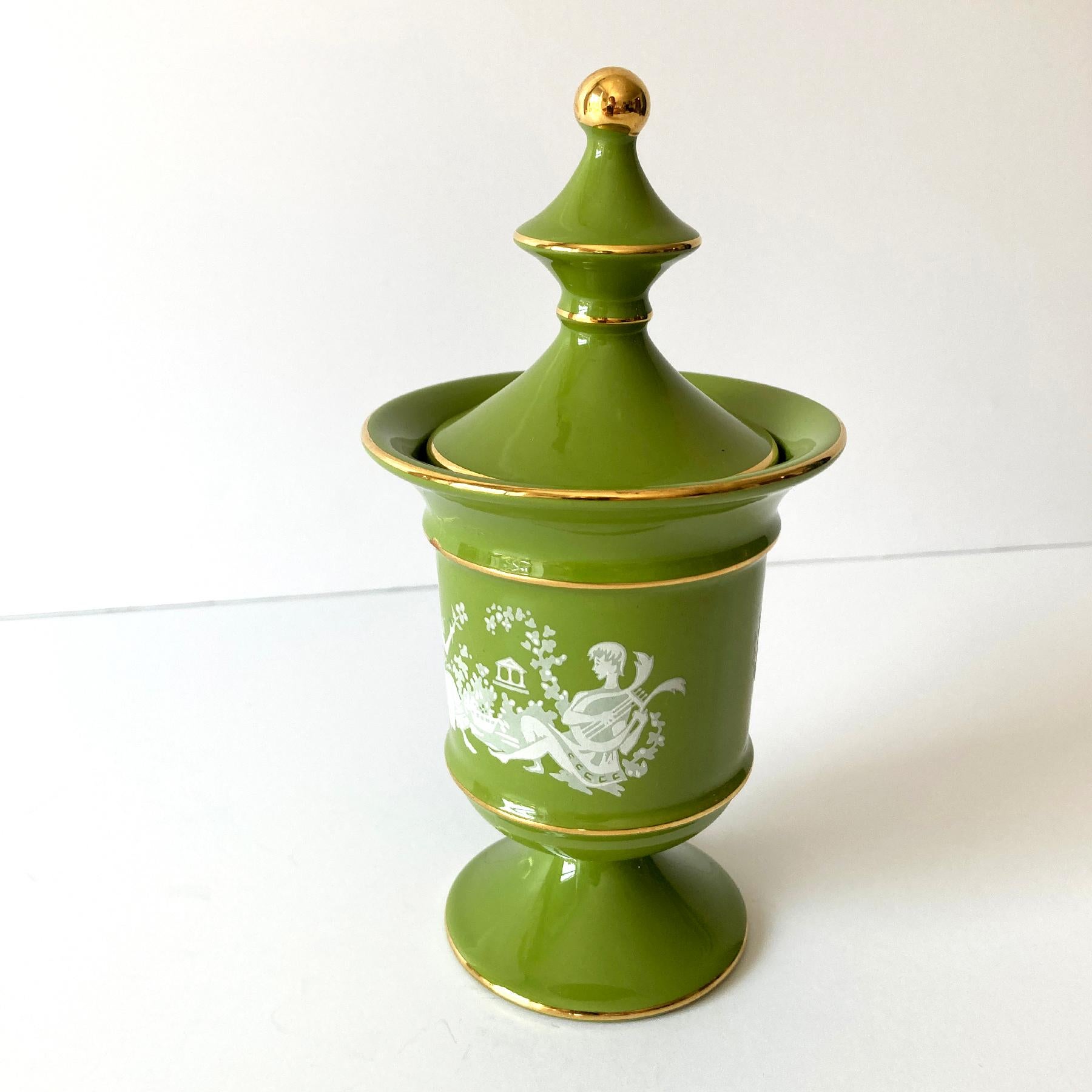 Precioso tarro/urna de cerámica con tapa redonda de color verde musgo y dorado italiano. El tono verde contrasta maravillosamente con los detalles dorados y el dibujo blanco que envuelve la pieza. Su pequeño tamaño hace que esta pieza sea versátil;