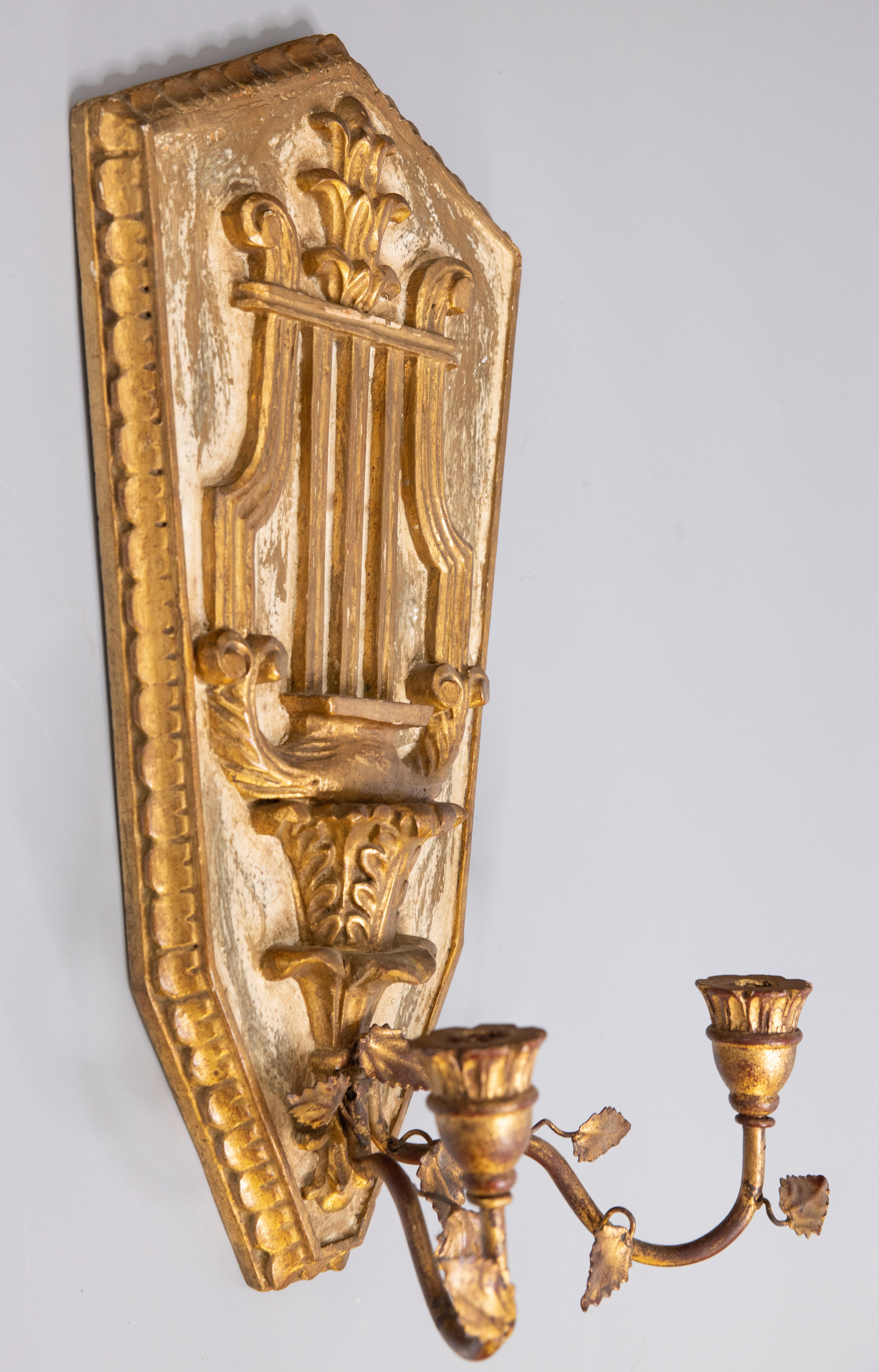 A lovely Italian Neoclassical style giltwood two arm candle wall sconce, circa 1950. This gorgeous candelabra is decorated with a carved gilded wood lyre and acanthus leaf design with tole arms and scrolling leaves. It's a nice large Size and would