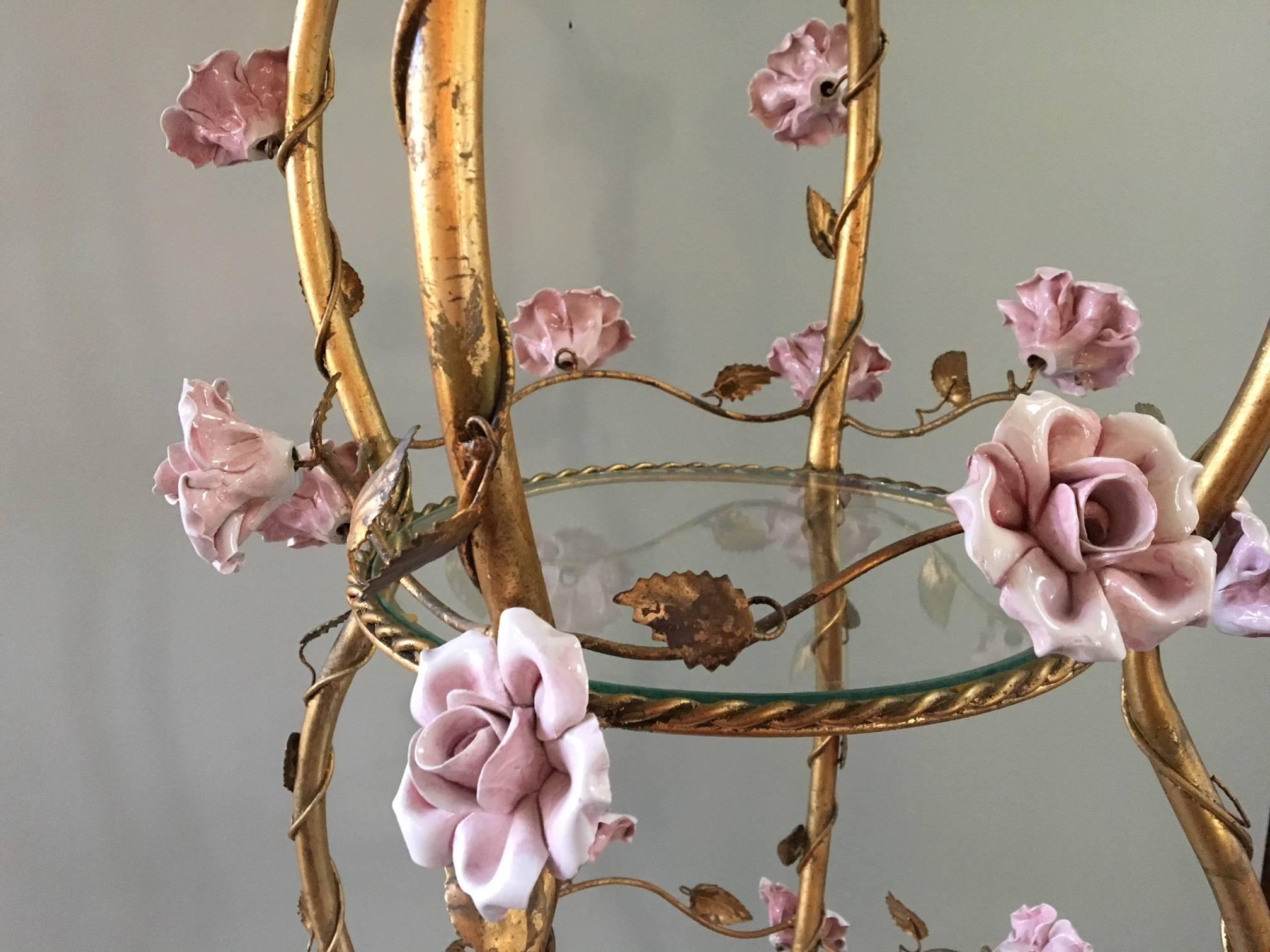 Large Italian tole étagère features gold gilt finish and 37 handcrafted ceramic roses. Single light shines down through glass shelves. Original 