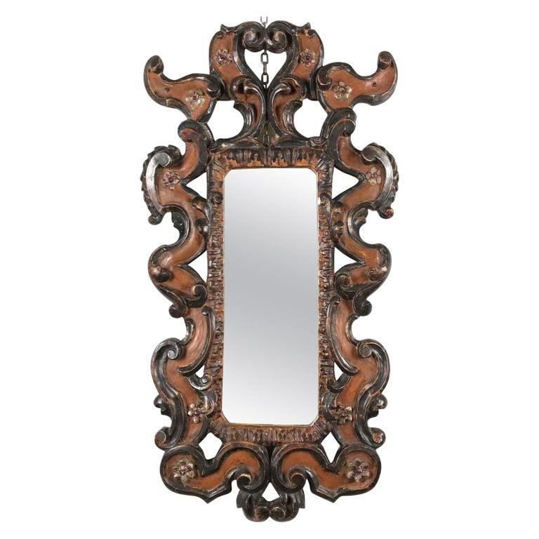 A lovely Italian vintage mirror with acanthus leaf, floral and scrolling relief hand-carving, a Renaissance Revival style vertical frame with original red coral painting of Armenian bolus and parcel silver-leaf floral decorations. The glass mirror