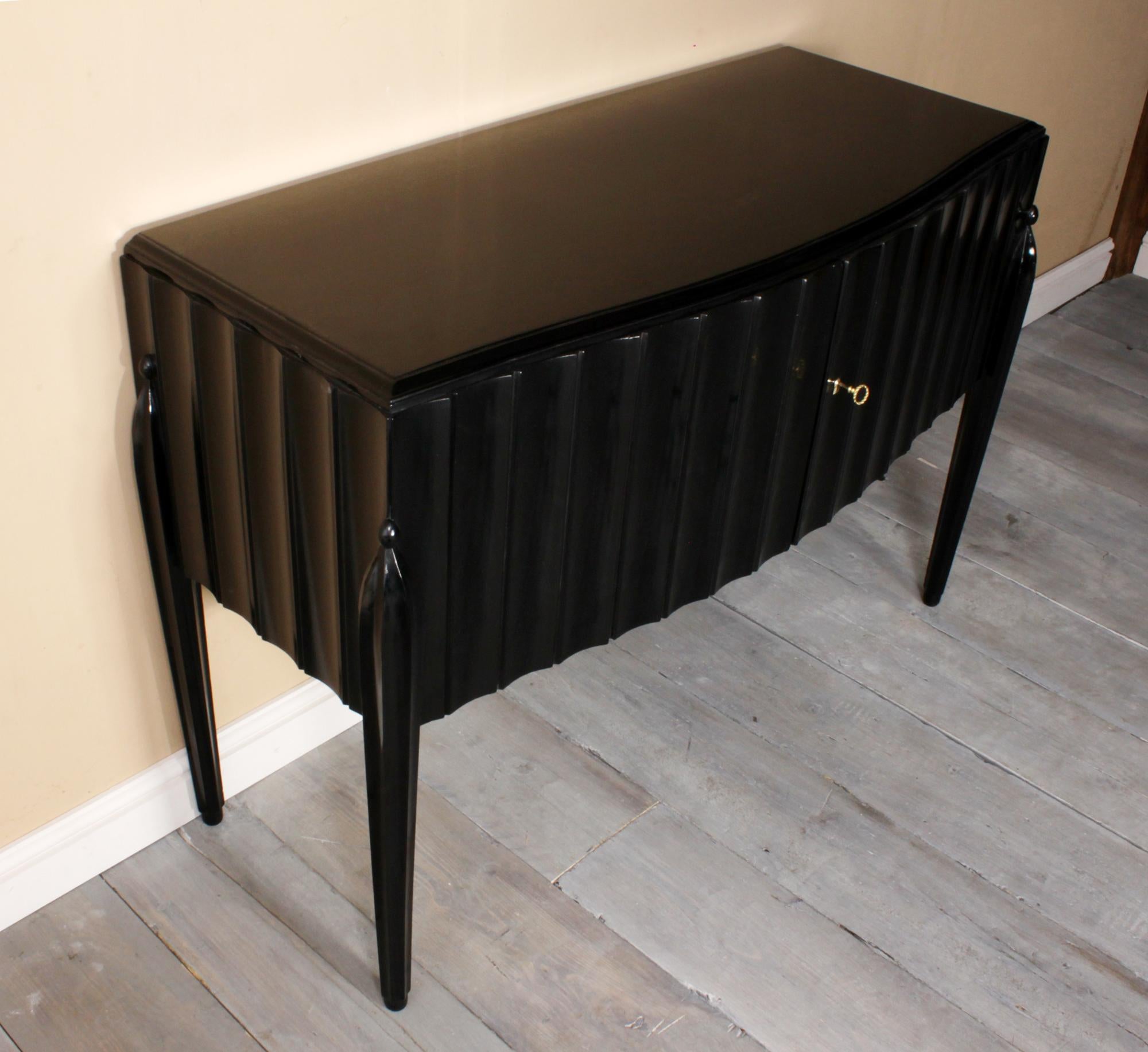 Italian fluted Art Deco sideboard in black piano lacquer, circa 1930.

A small Italian two door sideboard, fluted body on fluted legs, has the look of Jacques Emile Ruhlmann finished in ebonized piano lacquer with gloss shine, has been fully hand