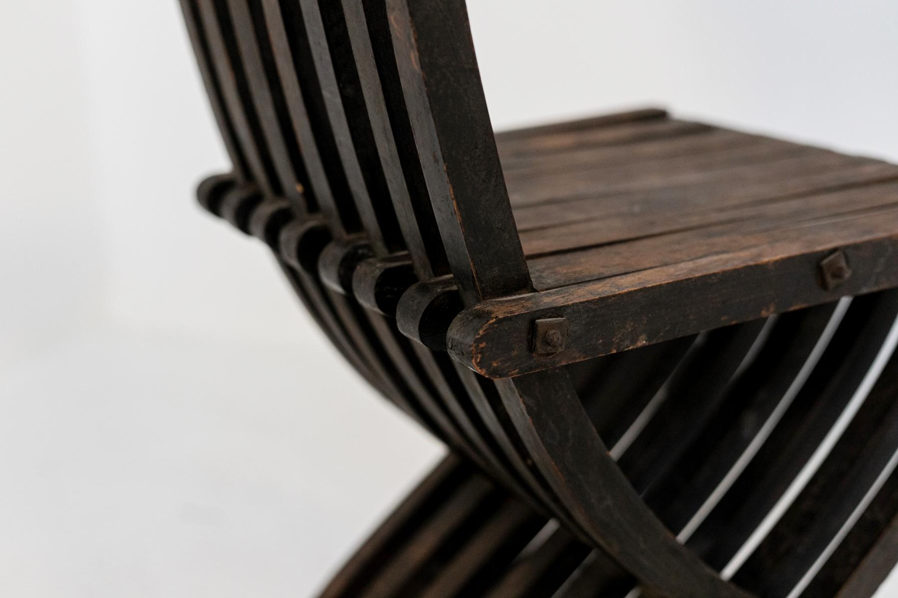 The vintage chair is from the 30s and is of fine Italian manufacture. Made in fine dark wood with inlays. The unique chair has wooden intertwined stave that through a mechanism, close on themselves making the chair partially foldable. The top of the