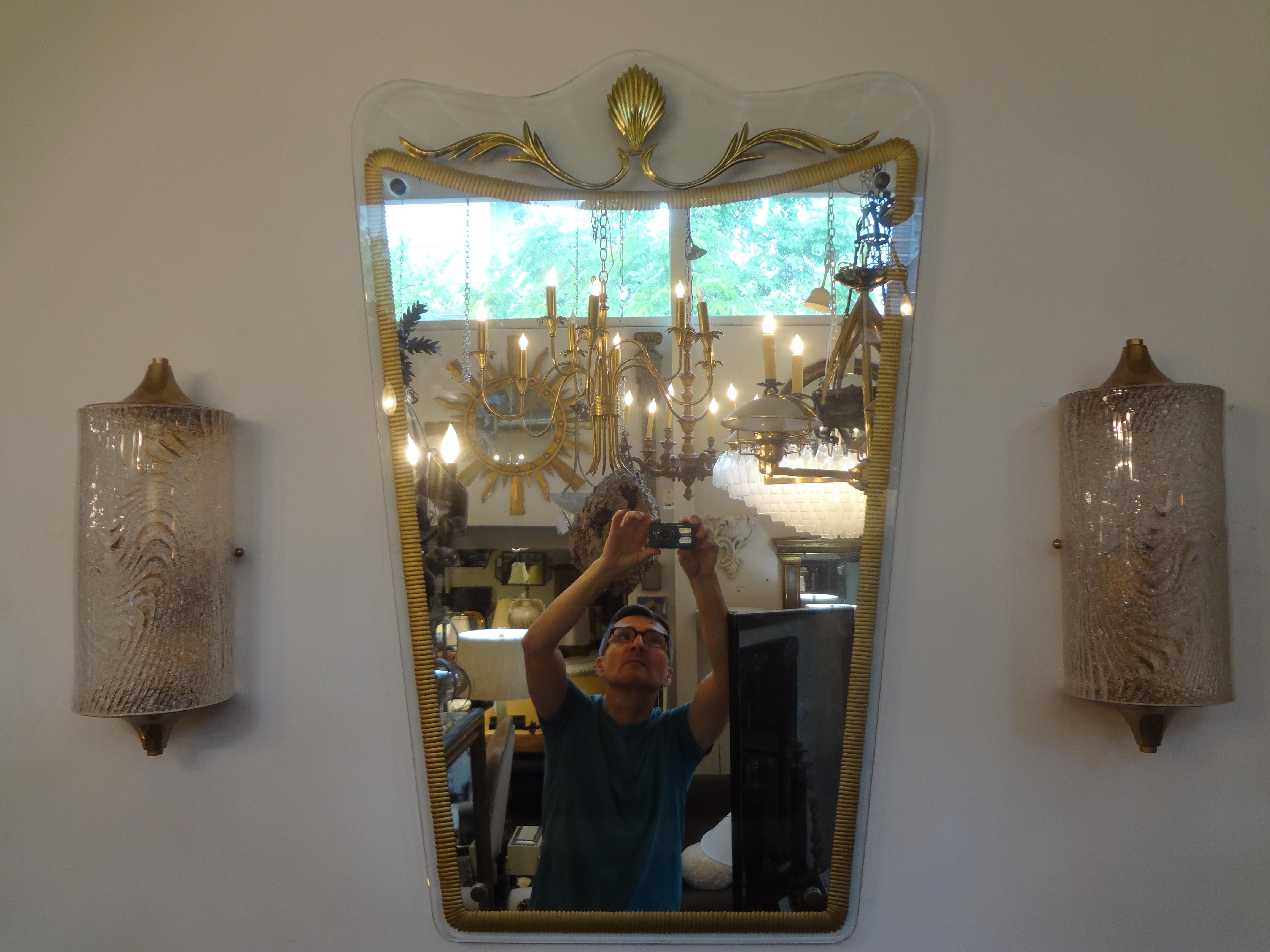 Stunning Italian neoclassical style mirror in the manner of Pietro Chiesa for Fontana Arte or Cristal Arte. This fabulous Italian midcentury mirror has an unusual gilt decorated design. This mirror would work well in an entrance hall, powder room,